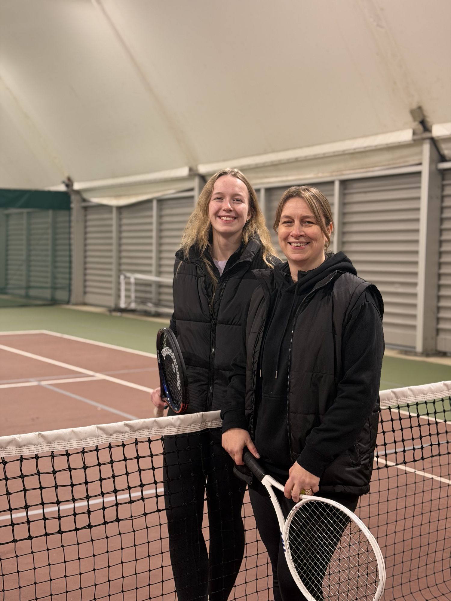 Two players smiling at the net on the indoor courts