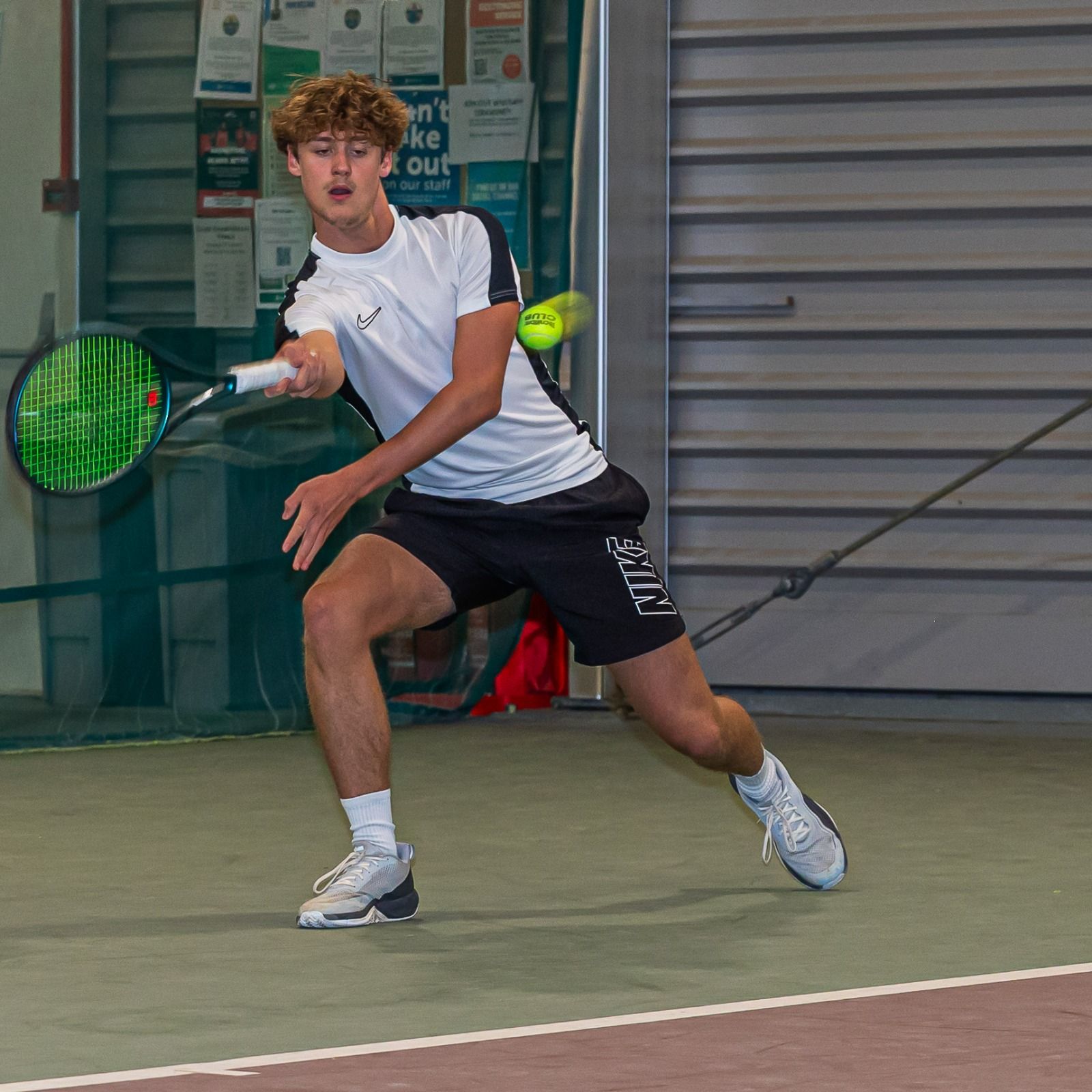 Player lunging for a forehand on the indoor courts at War Memorial Park