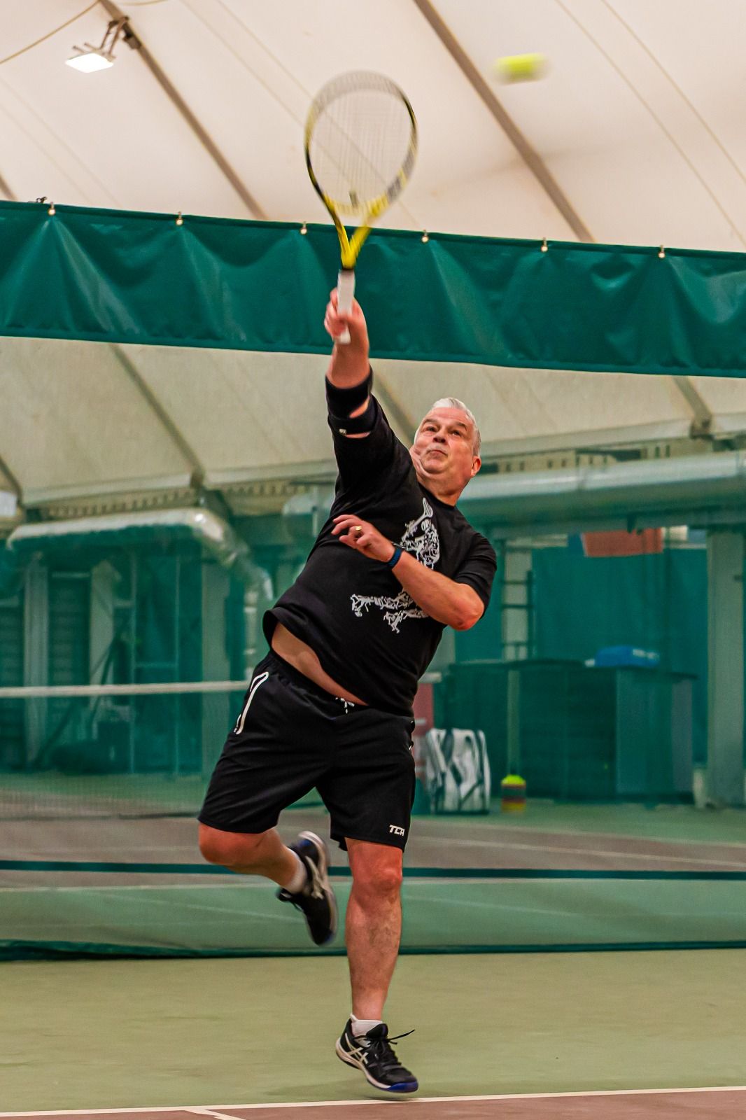 Player hitting an overhead smash indoors