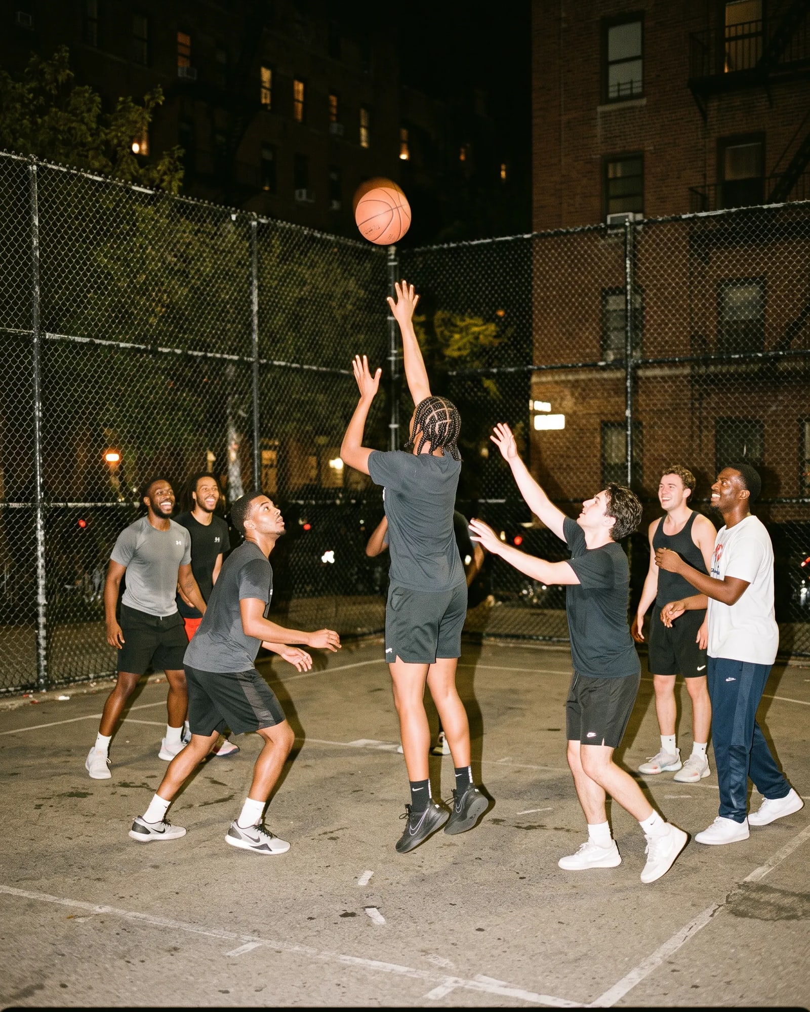 A pickup basketball game under the lights, a shot in the air.