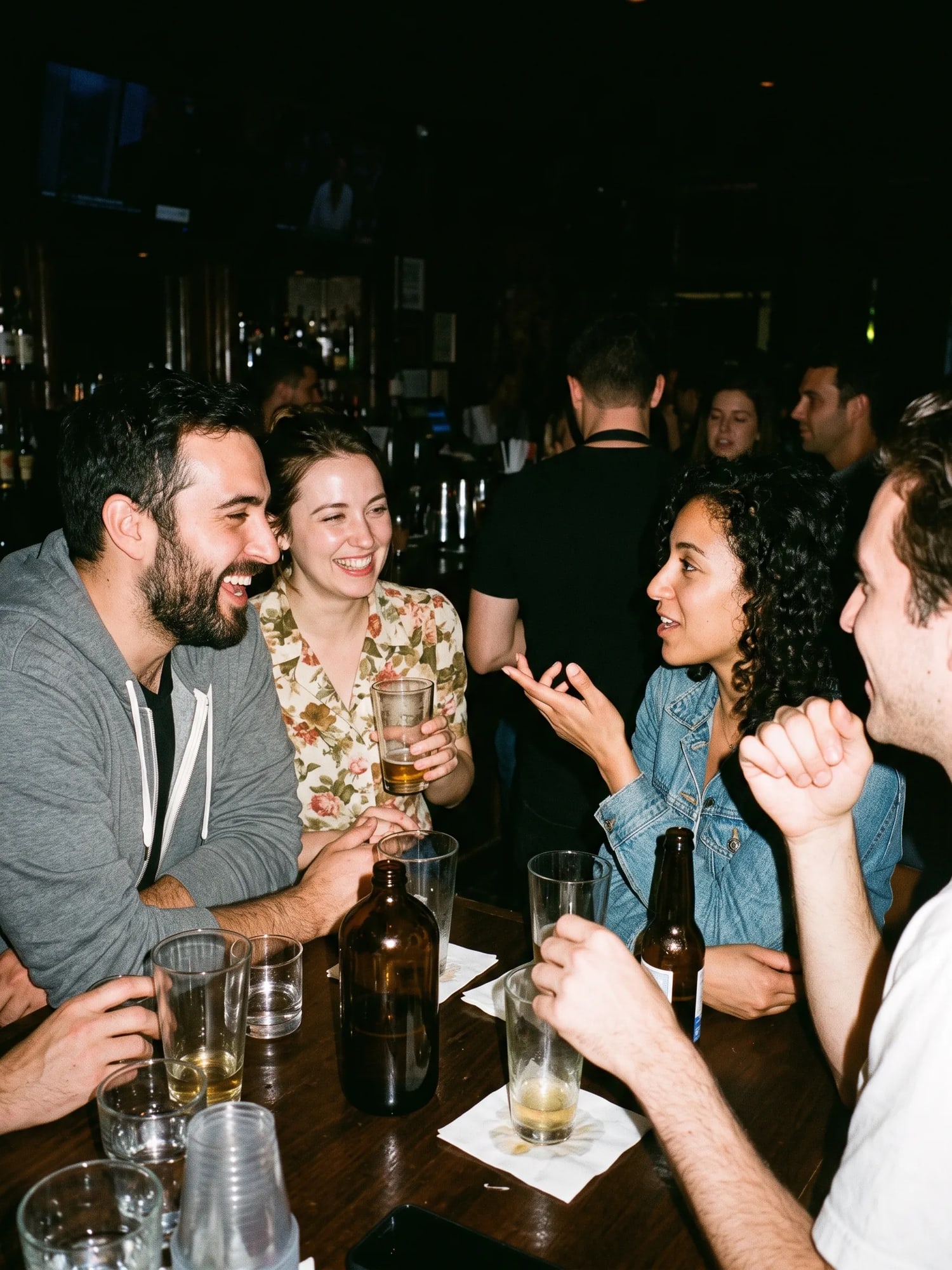 Friends crowded around a bar table, laughing over drinks.