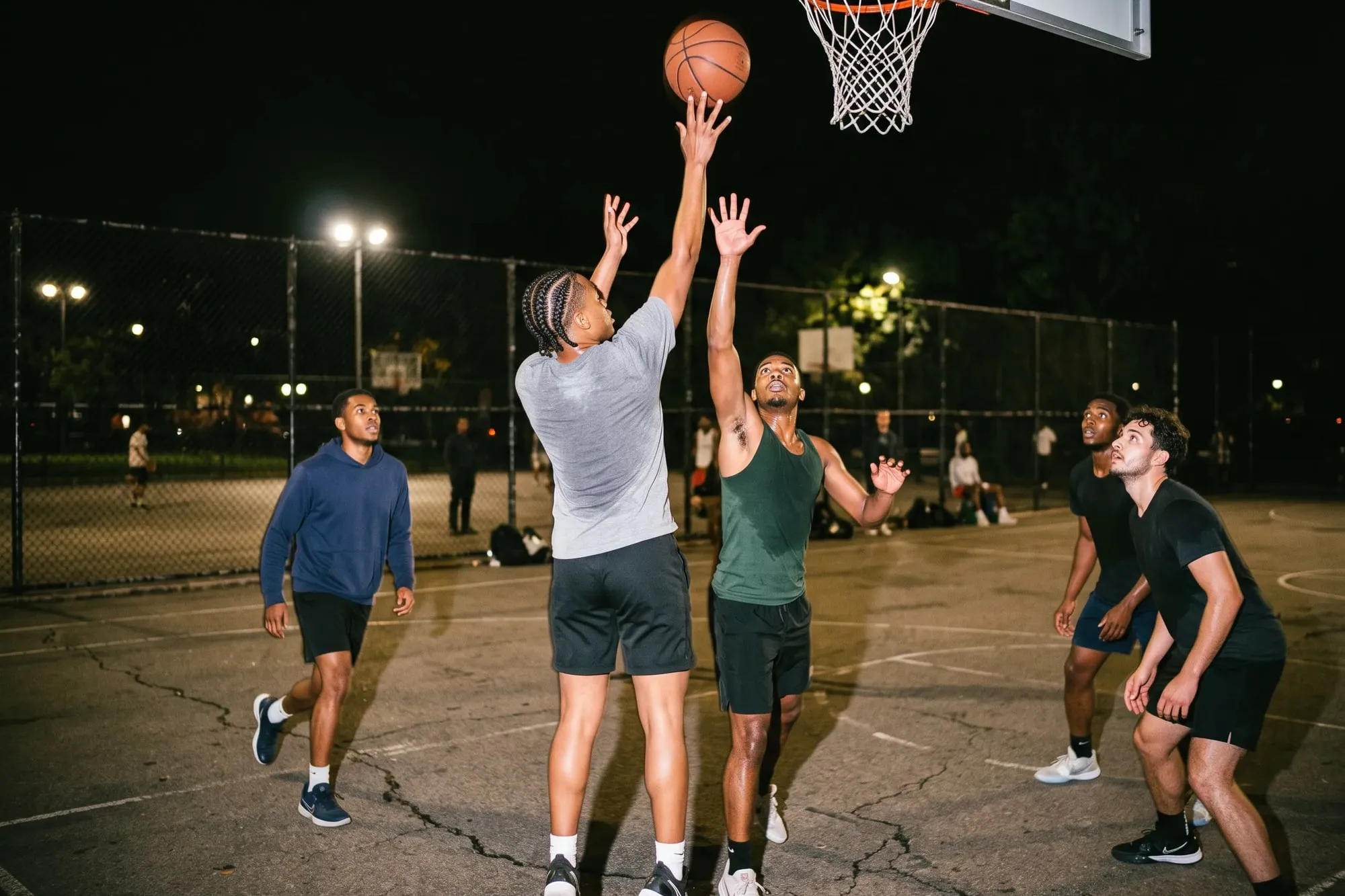 A pickup basketball game at night, one player going up for a shot.