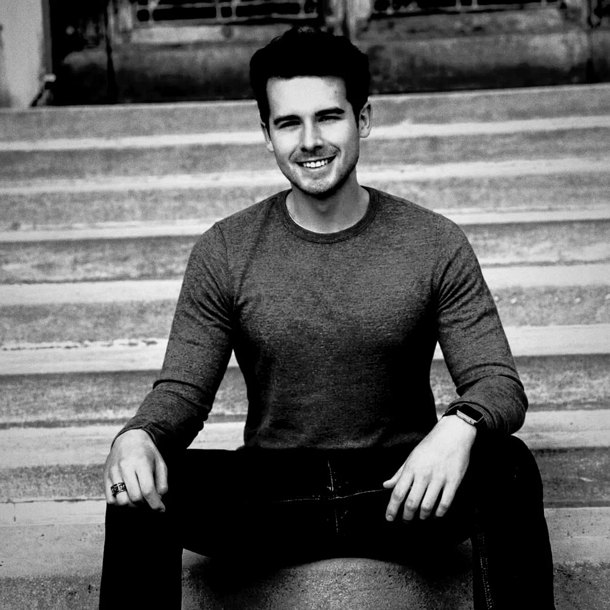 Peyton sitting on stone steps, smiling.