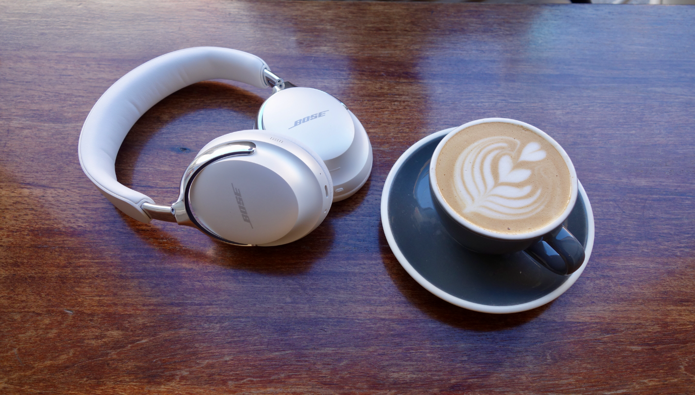 White and silver Bose’s QuietComfort Ultra 2 close up next to a specialty coffee
