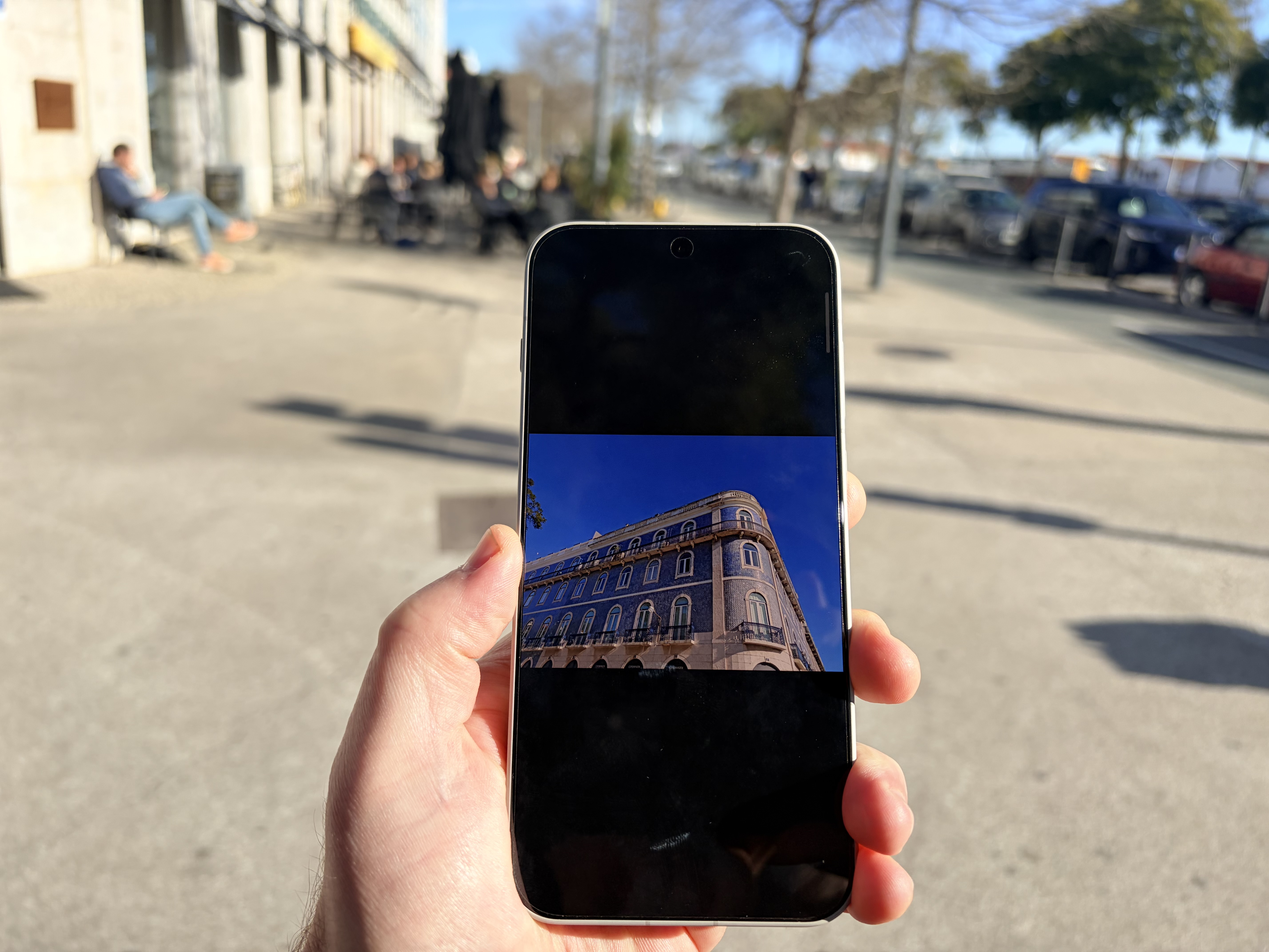 OnePlus 15 review, showing the screen brightness capability holding the phone outside and showing the camera capability. Lisbon tiled buildings. 