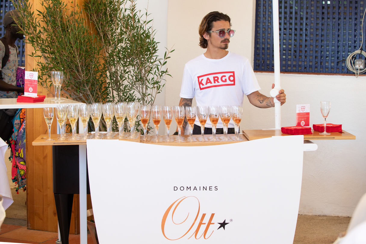 Bartender serving drinks at a Kargo event, with branded glassware and a Domaines Ott bar display