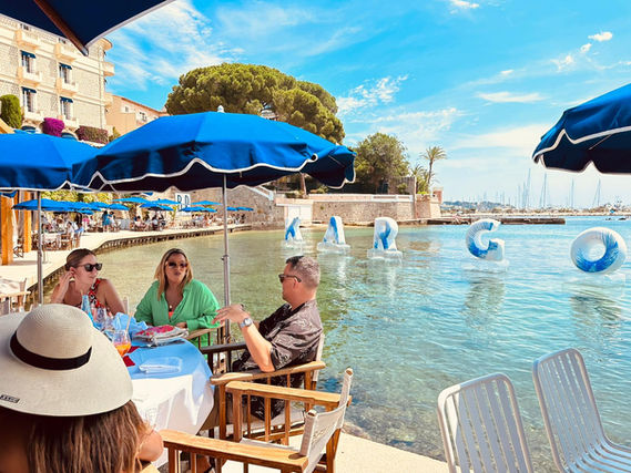 Guests dining waterside at Kargo's Cannes Lions event with "KARGO" balloons floating in the water