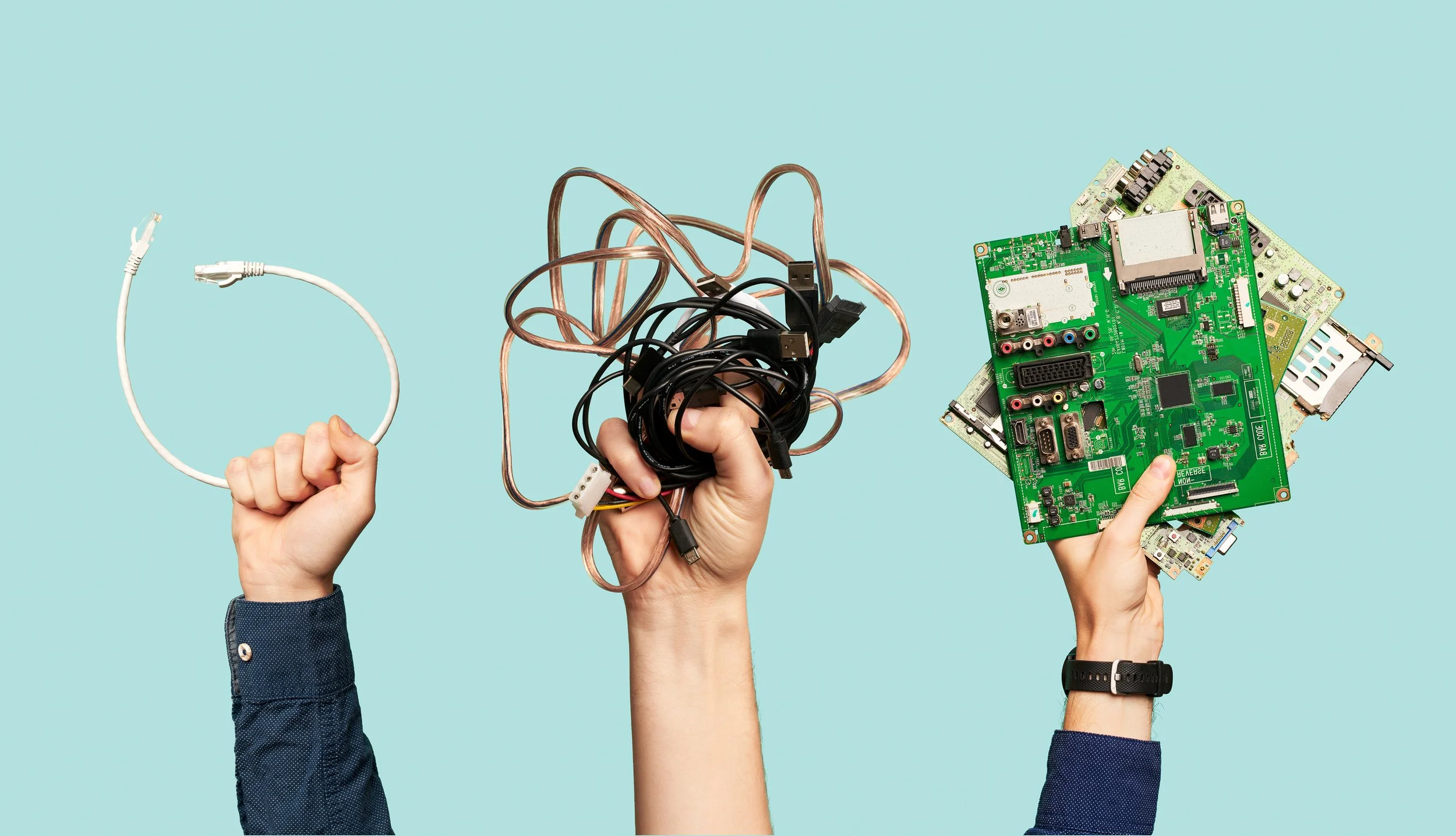 Three raised hands against a light blue background holding electronic items: the left hand holds a white Ethernet cable, the middle hand holds a tangled bunch of black and copper-colored cables, and the right hand holds multiple green circuit boards.