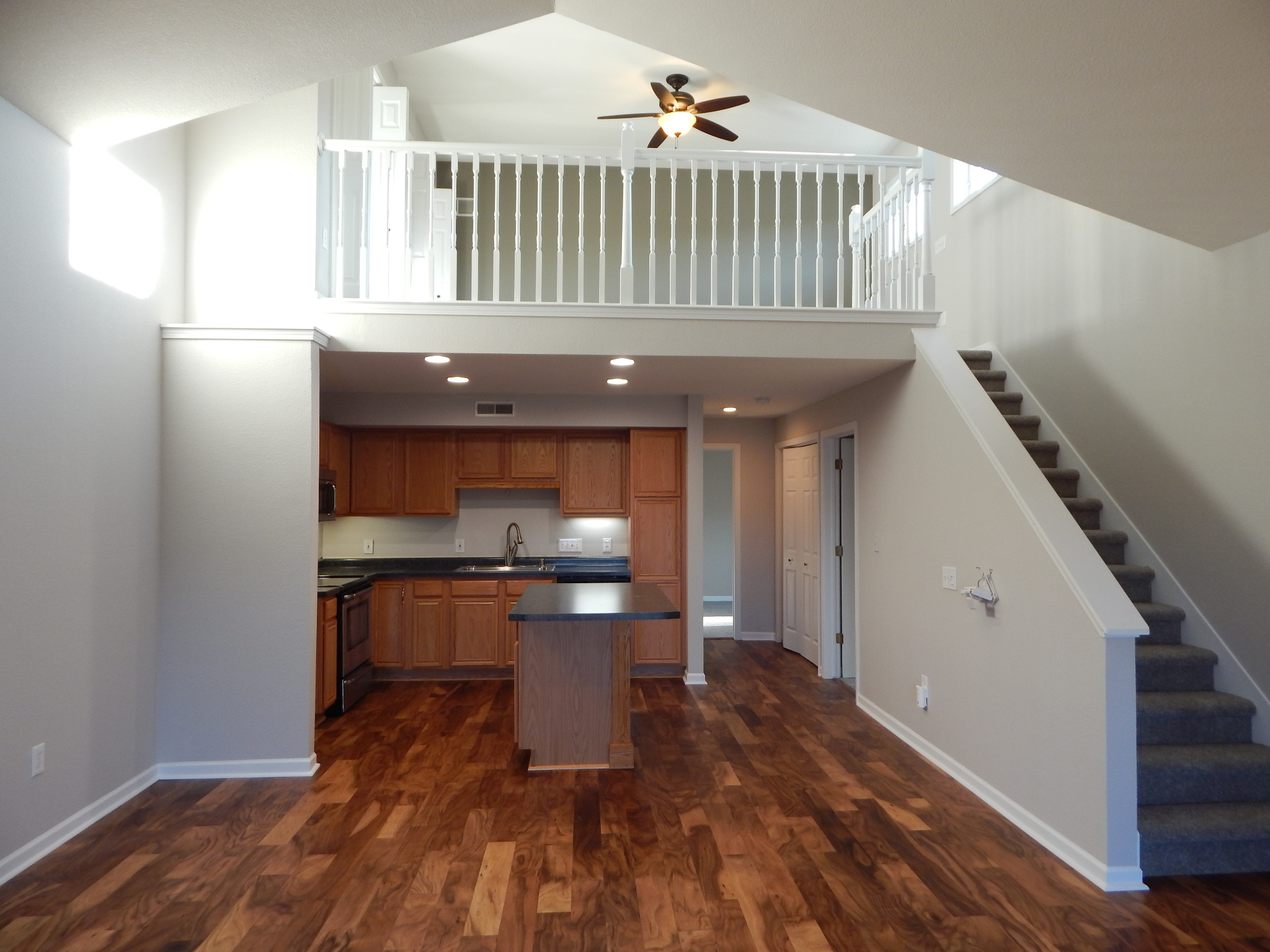 Pewaukee condo living area after renovation, with wood flooring, open kitchen and stairs