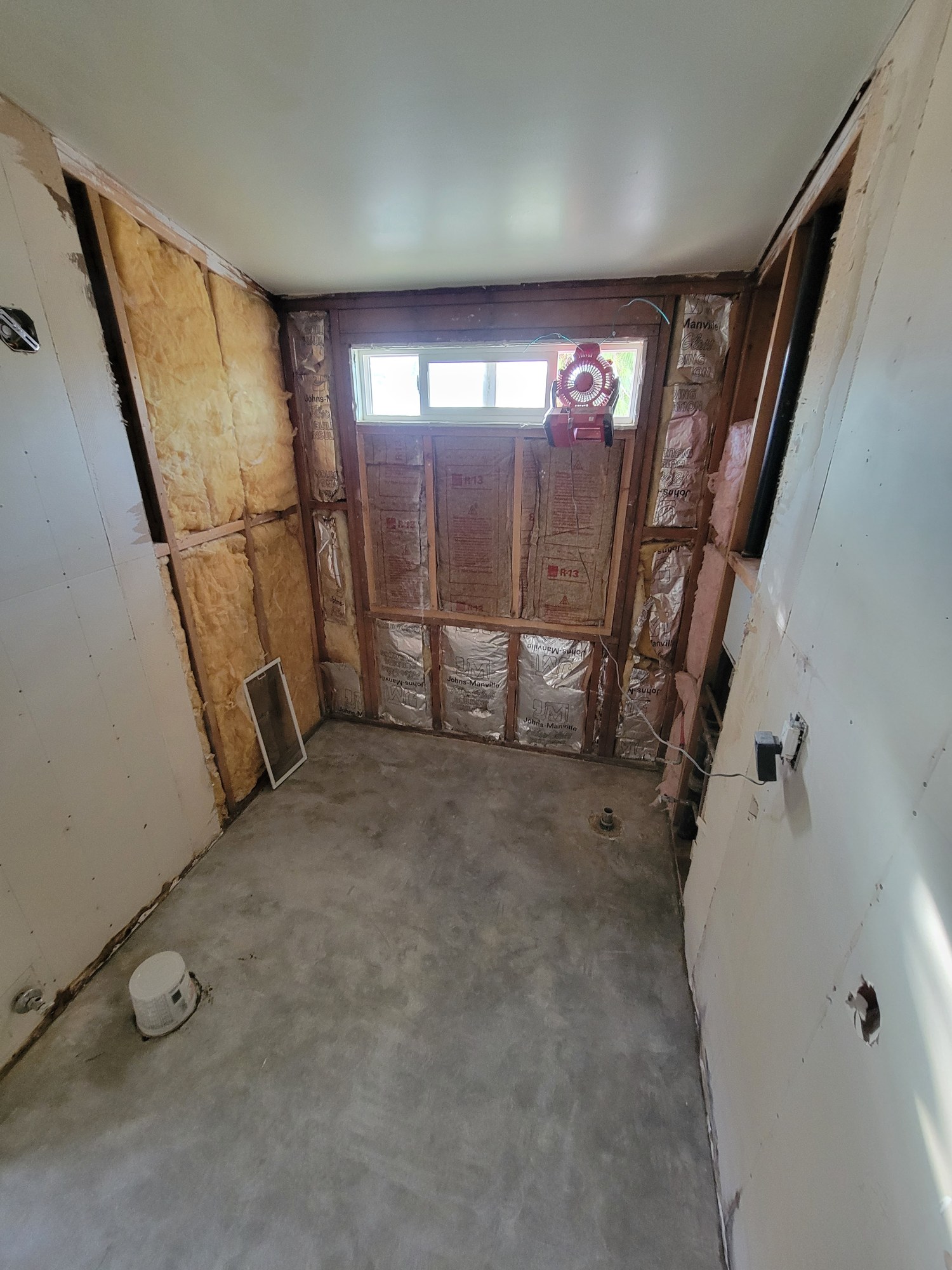 Bathroom during demolition with wall and fixture areas opened for renovation.
