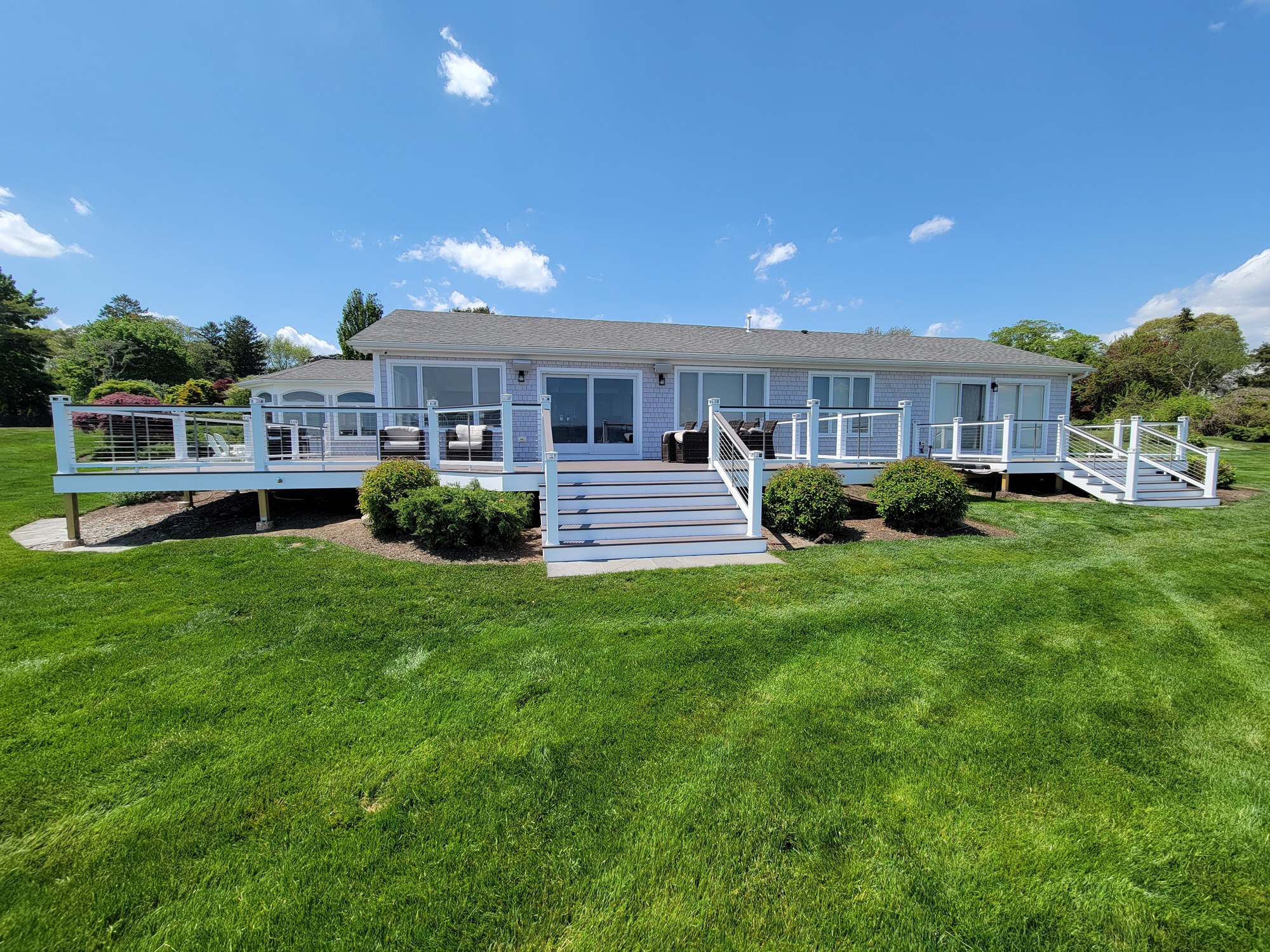 Completed coastal deck in Warwick Neck with light PVC decking and cable railing.