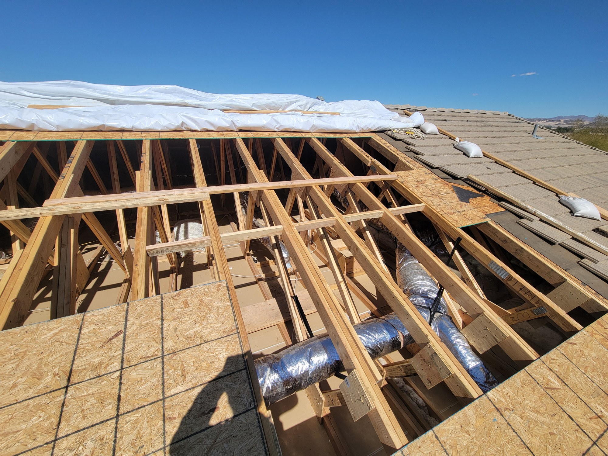 Wide view into opened roof framing with exposed trusses and mechanical services.