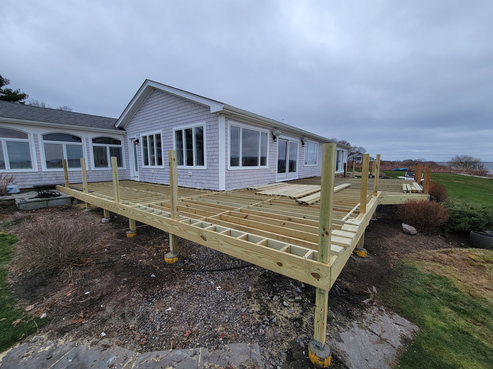 Deck framing rebuild in progress with new lumber integrated into retained structure.