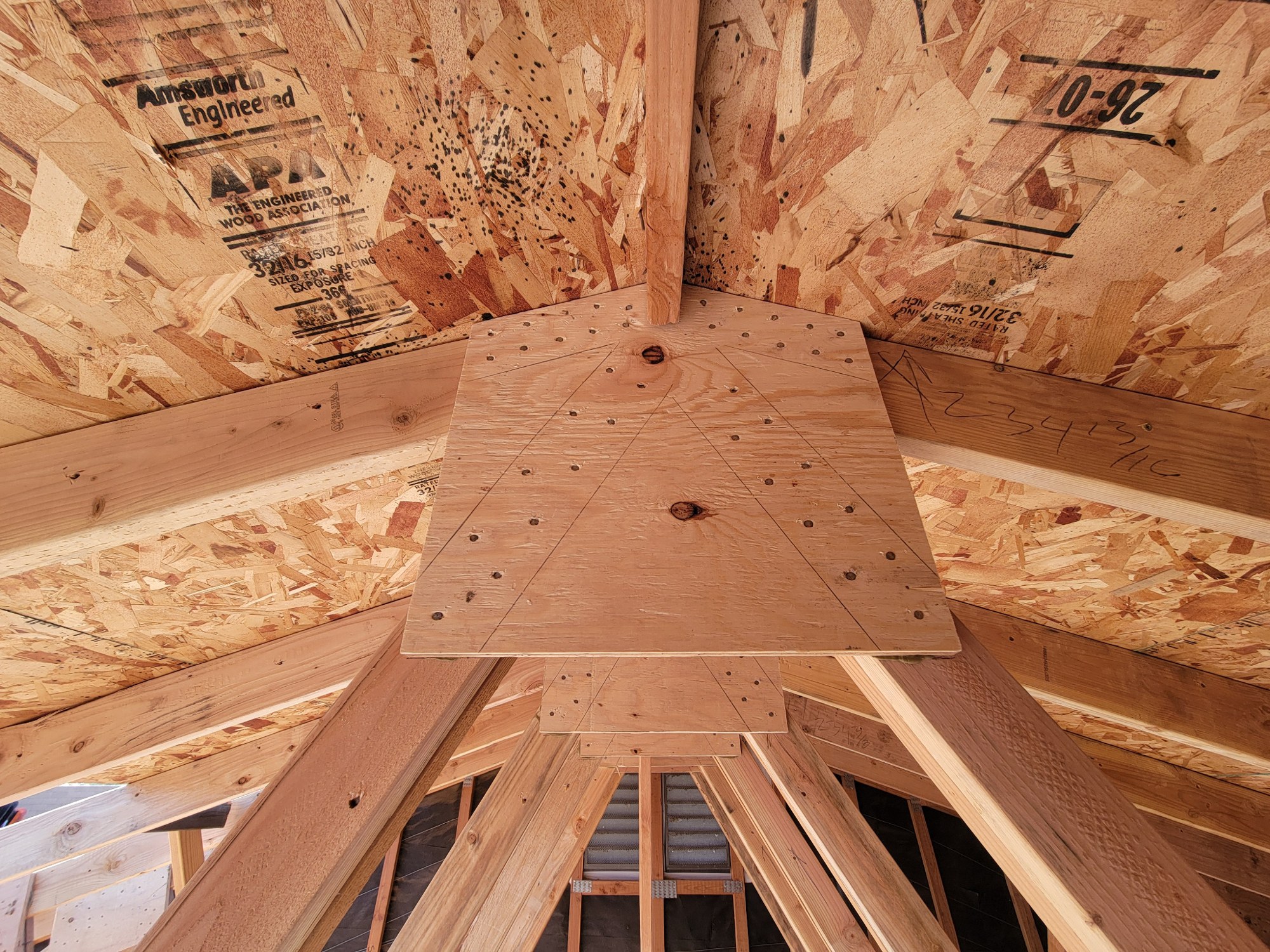 Close-up of plywood gusset plate installed at a repaired roof-truss joint.