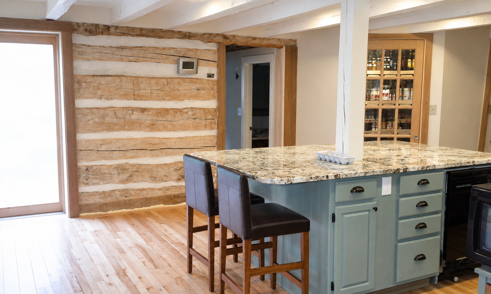The finished kitchen island beside the restored exposed log wall.