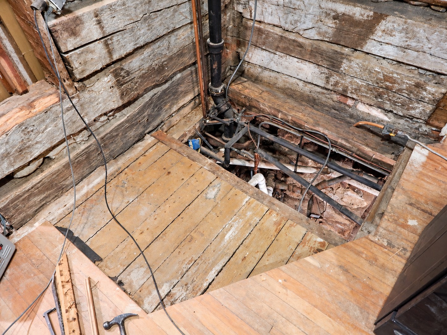 Floor sections opened beside the original logs for repairs and systems work.