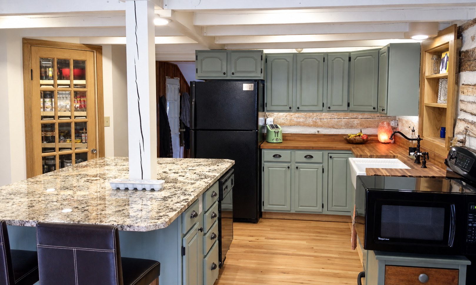 The finished kitchen with green cabinetry, granite island and farmhouse sink.