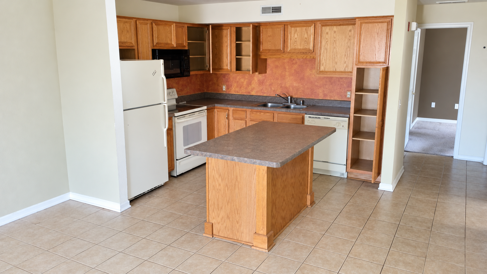 Pewaukee condo kitchen before renovation, with original oak cabinets, older appliances and tile flooring.