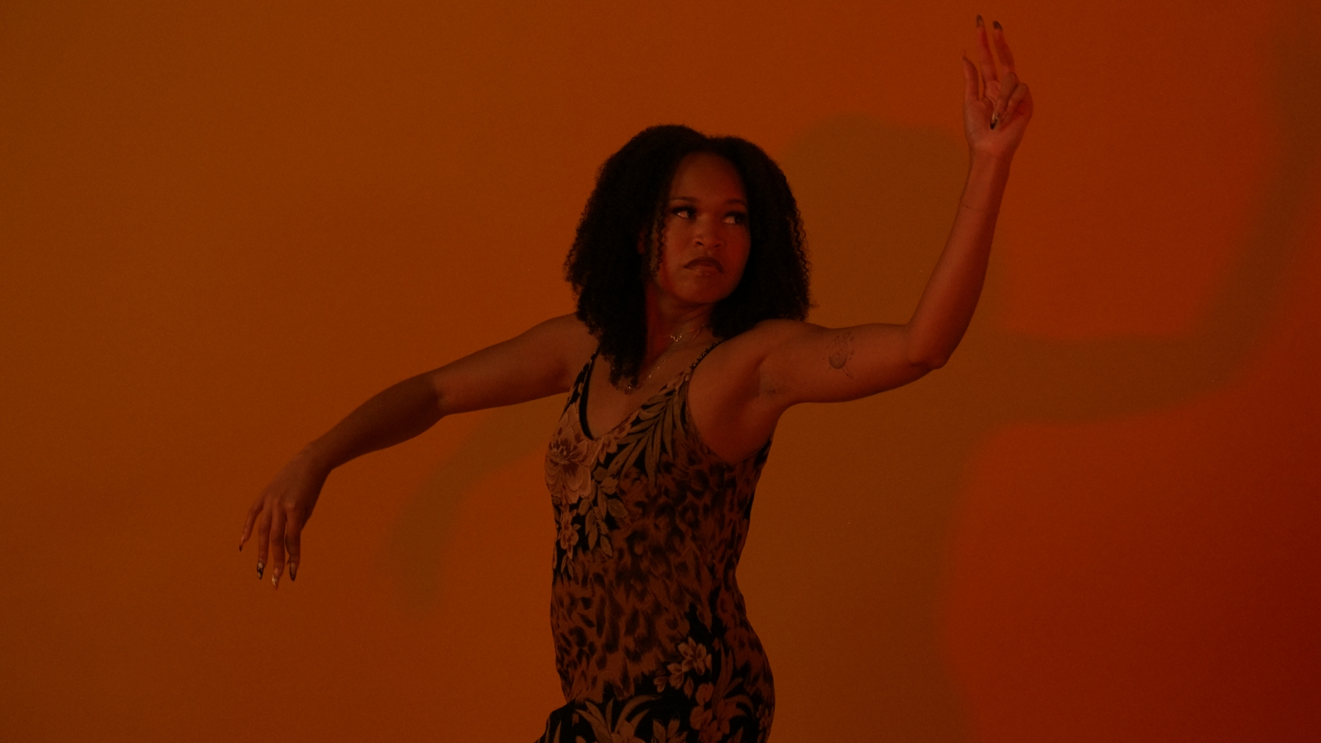 Veronica dancing in saturated red light, one arm raised