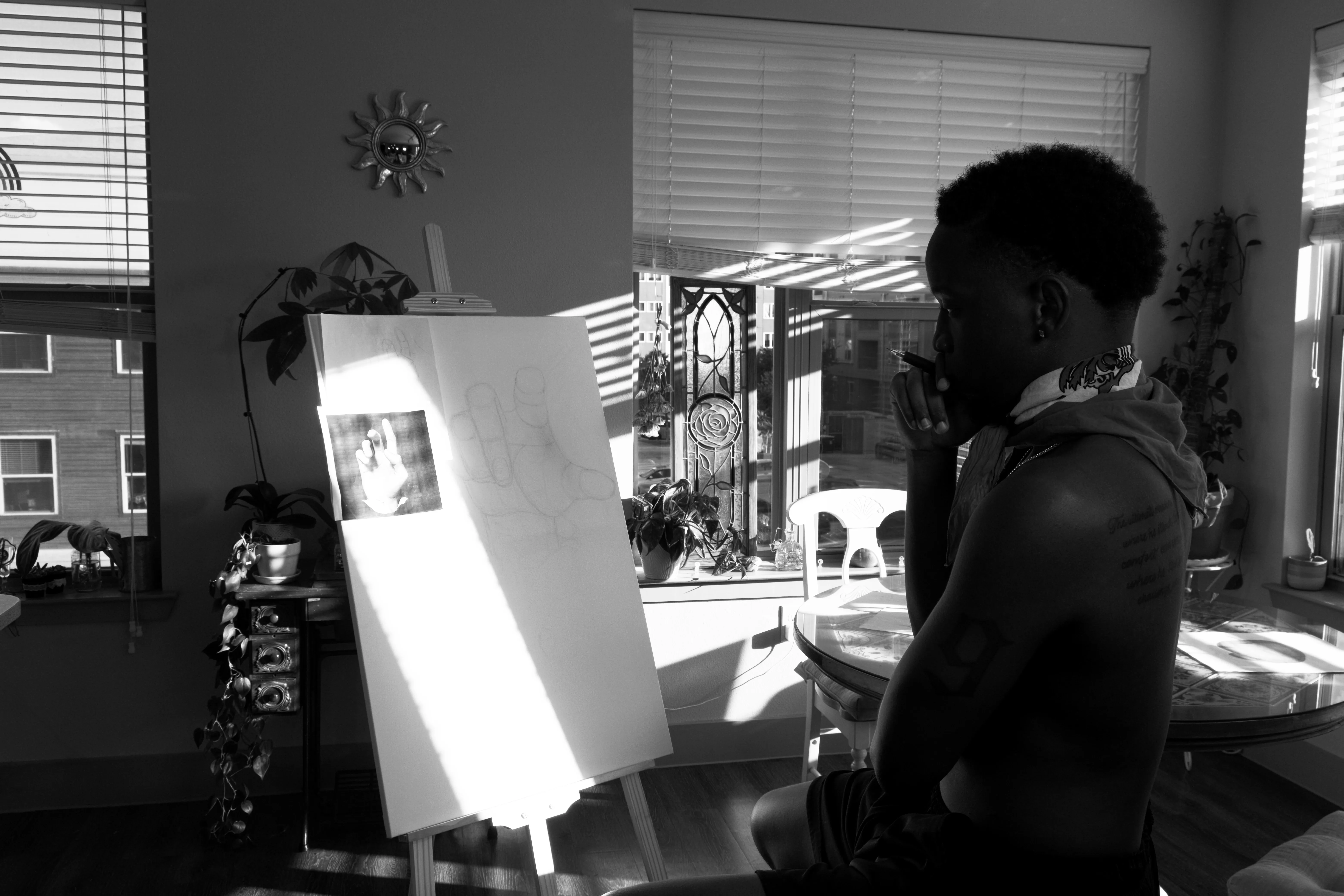 Otis seated at an easel, lit by striped window light