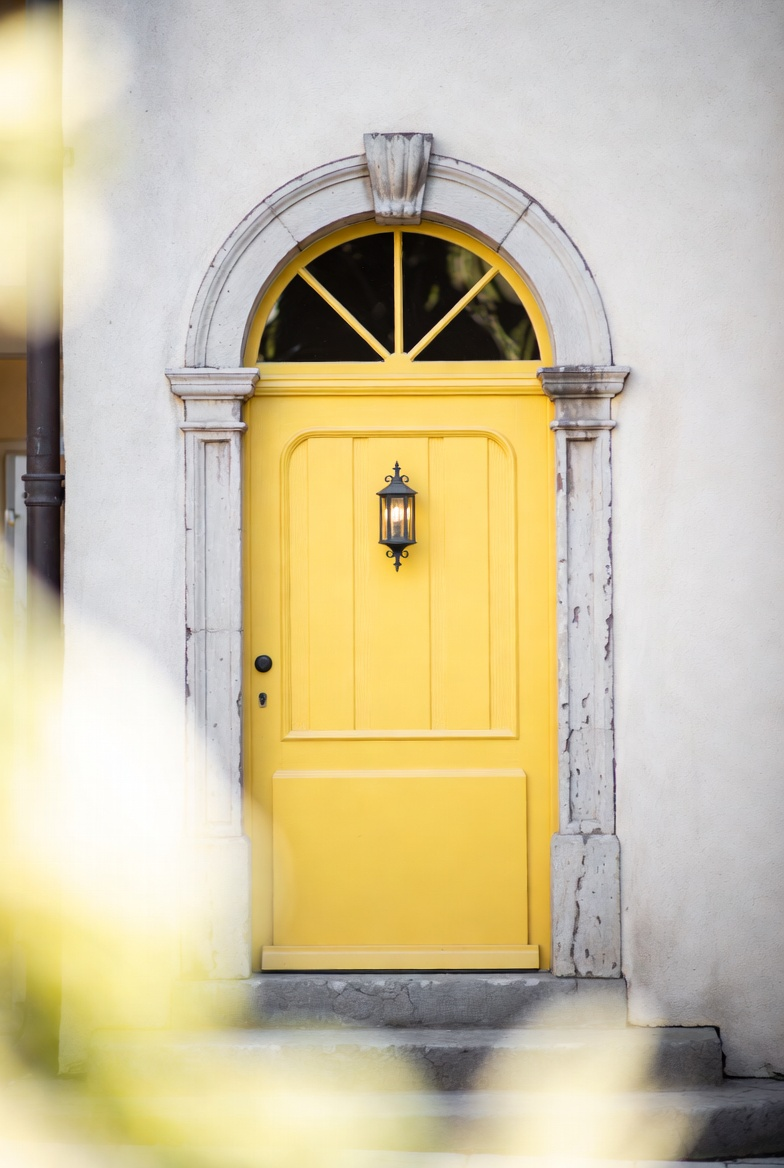 A yellow front door in an arched stone surround.