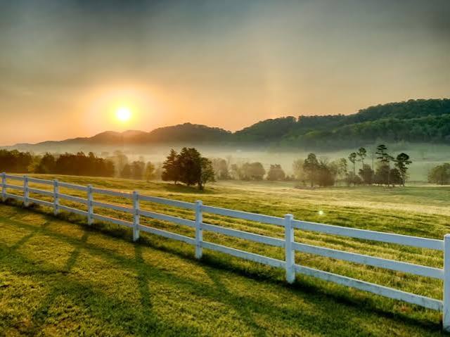 Sunrise over a white board fence and rolling Tennessee pasture