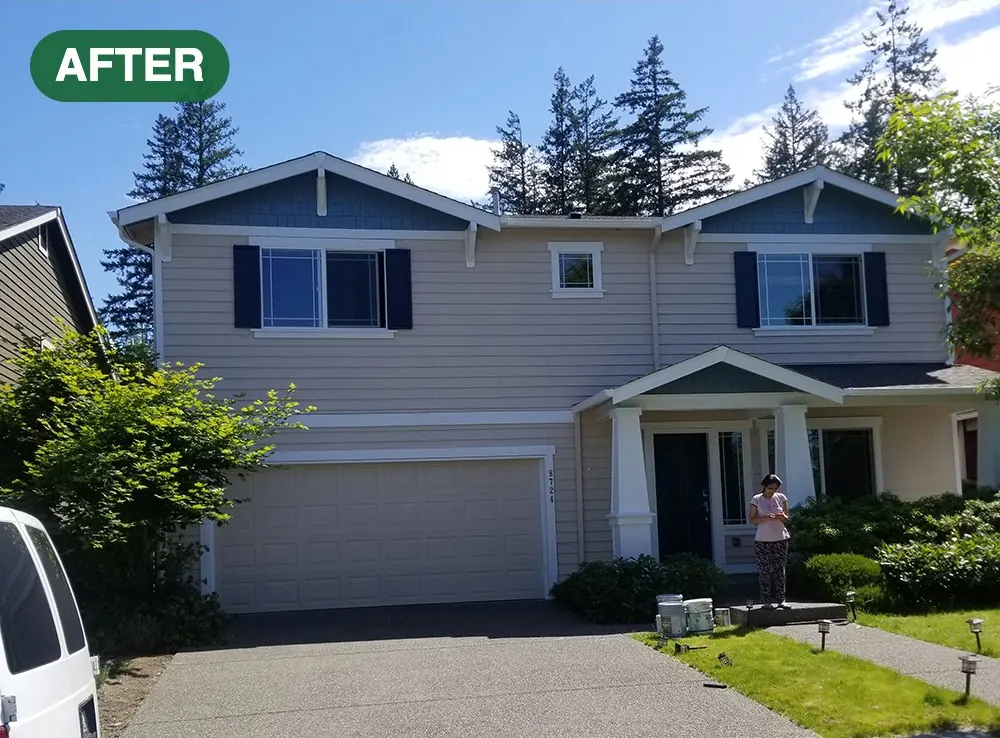 Two-story craftsman home repainted in a light neutral with dark blue shutters