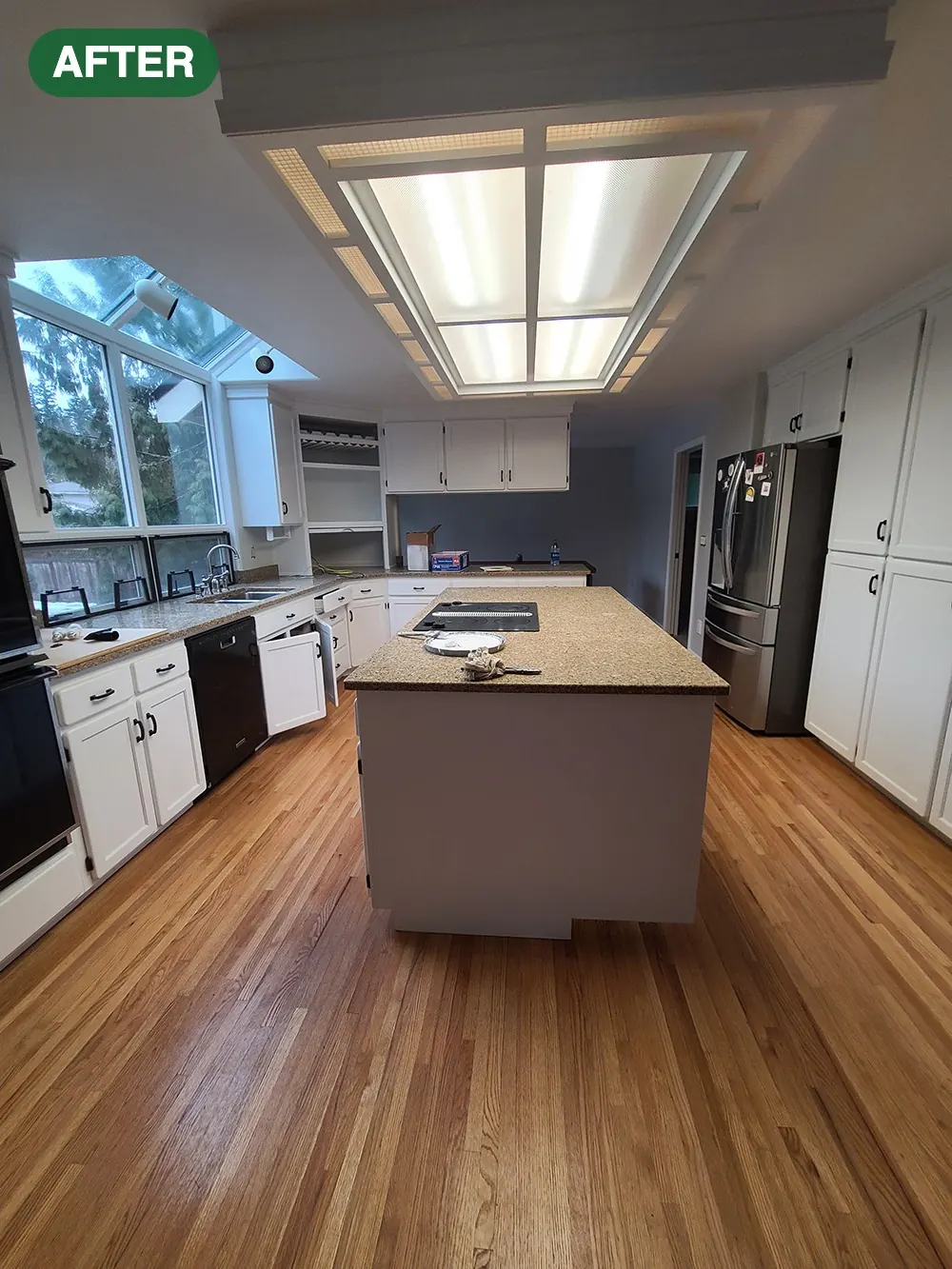 Kitchen with cabinets painted white and hardwood floors after an interior painting project