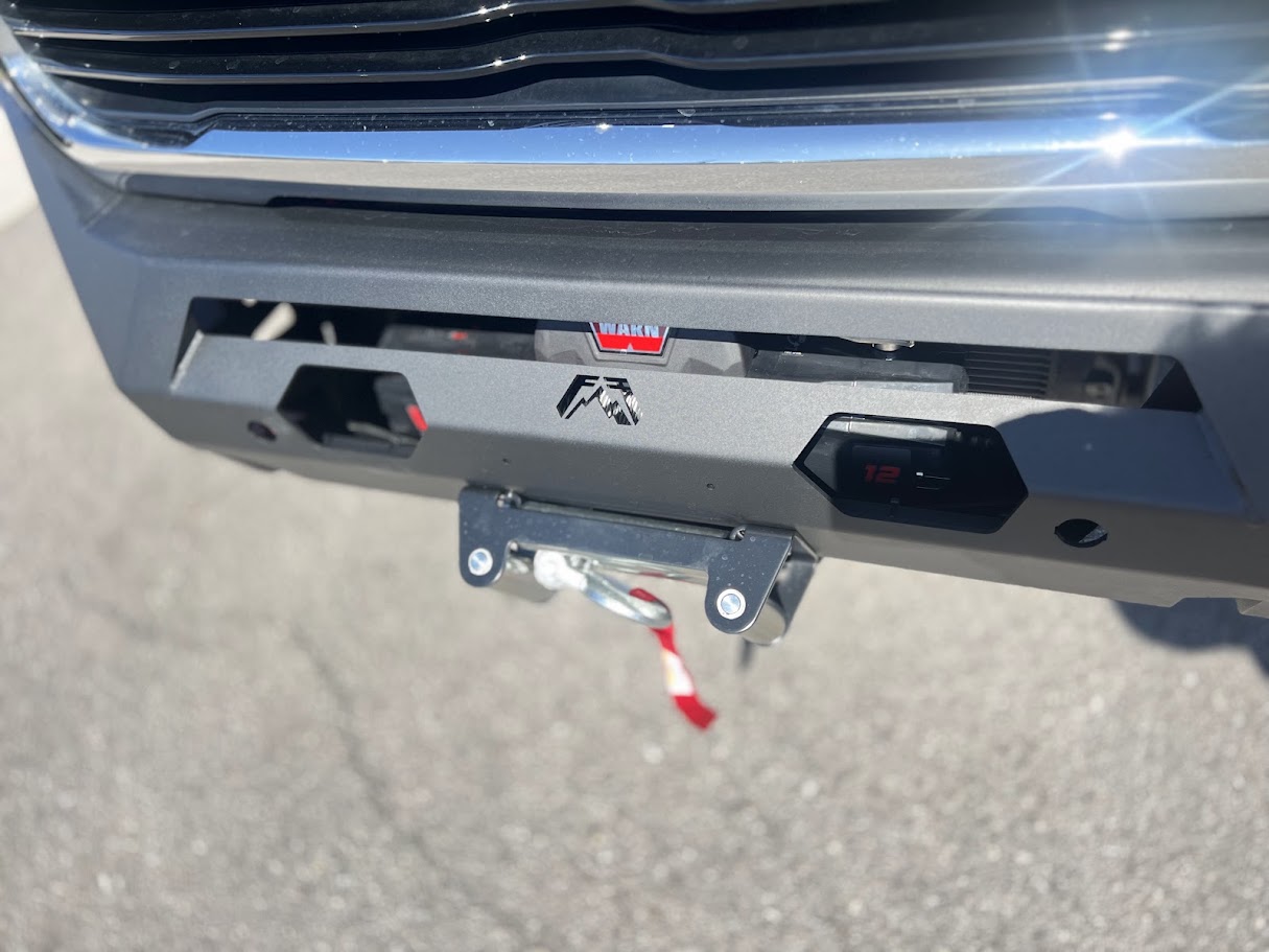 Black steel front bumper with winch installed on a pickup truck