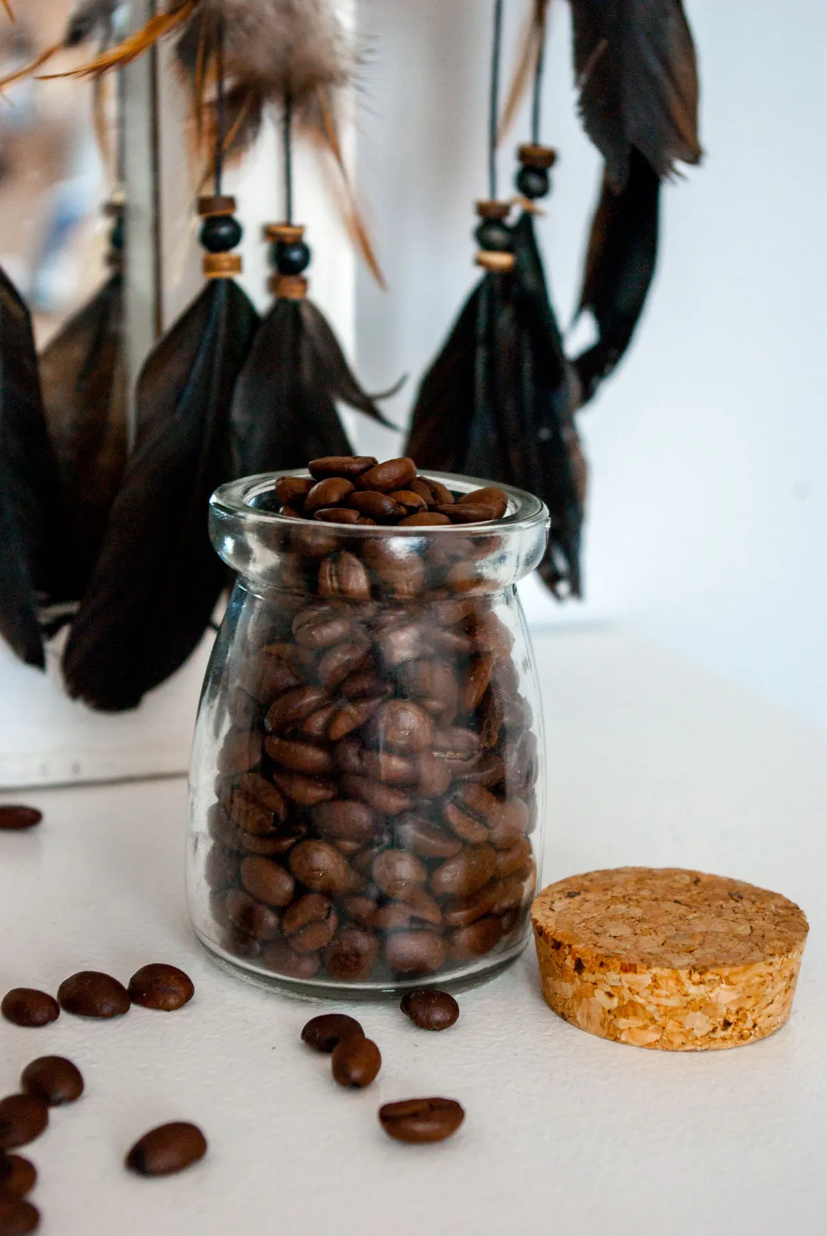 Coffee beans in a glass jar beside a cork lid