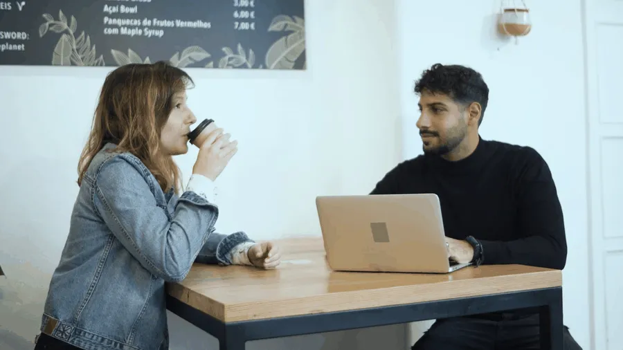 Two people discussing café plans over coffee and a laptop