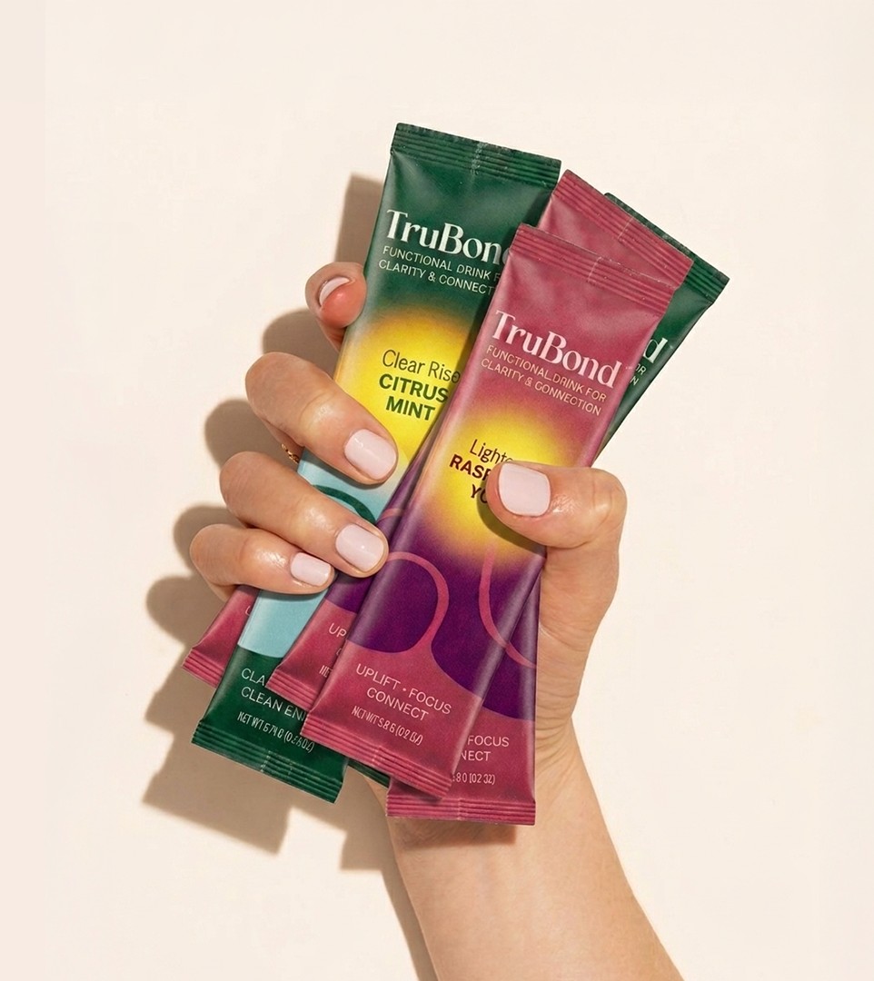 A hand holding TruBond drink mix sachets