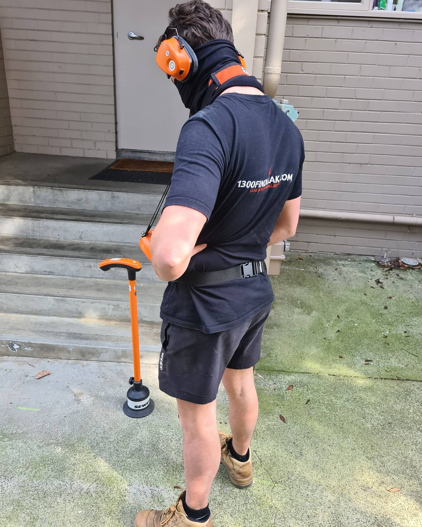 Technician listening for an underground leak with an acoustic ground microphone