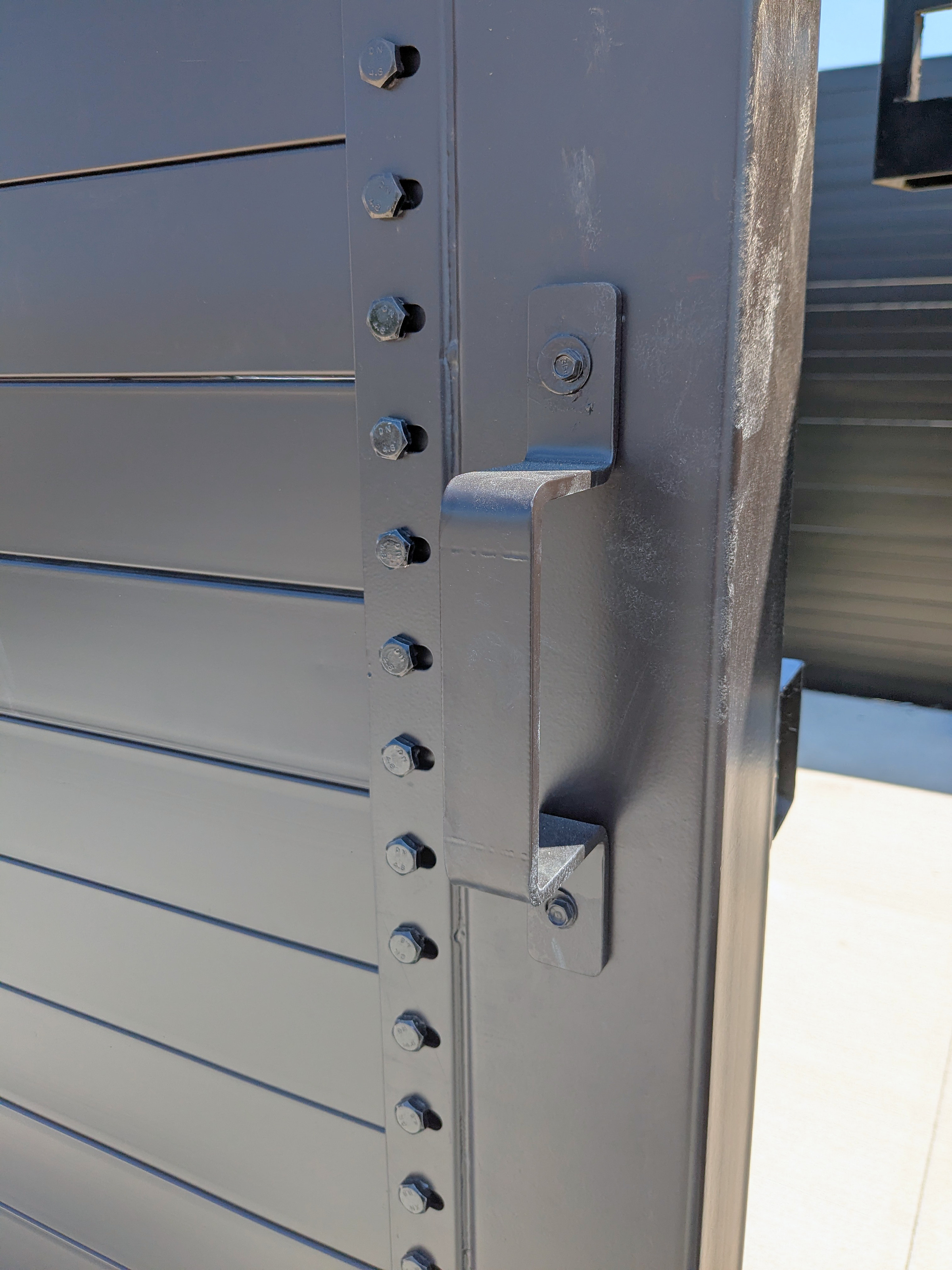 Welded steel handle and latch bracket on a structural steel enclosure gate