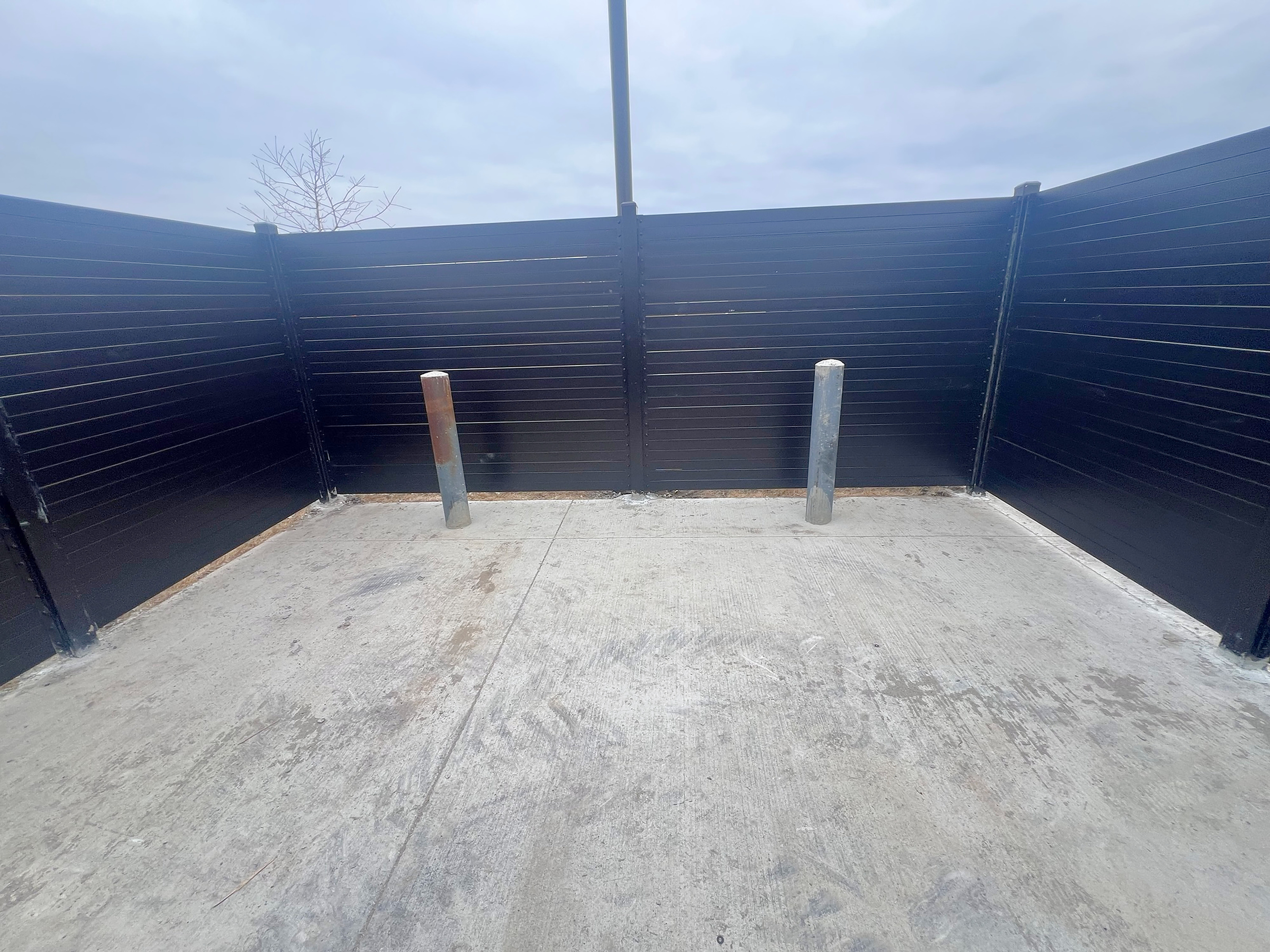 Tire storage enclosure interior with bollards, structural steel slats