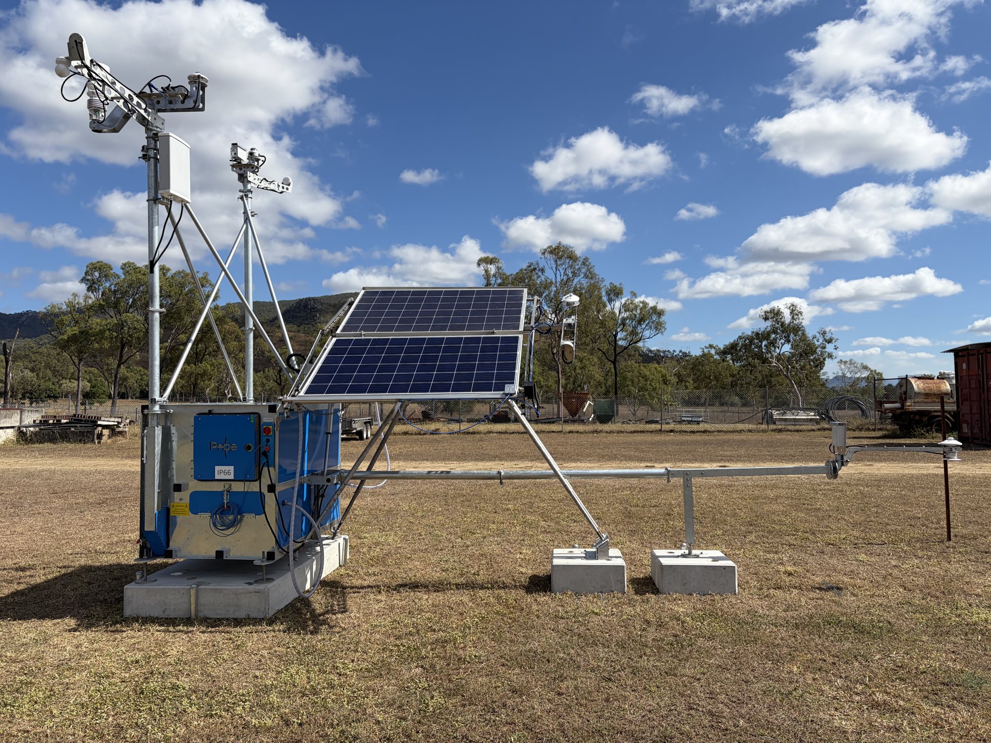 MetCube measurement station with sensor masts, reference modules and an albedometer arm in a grassy field
