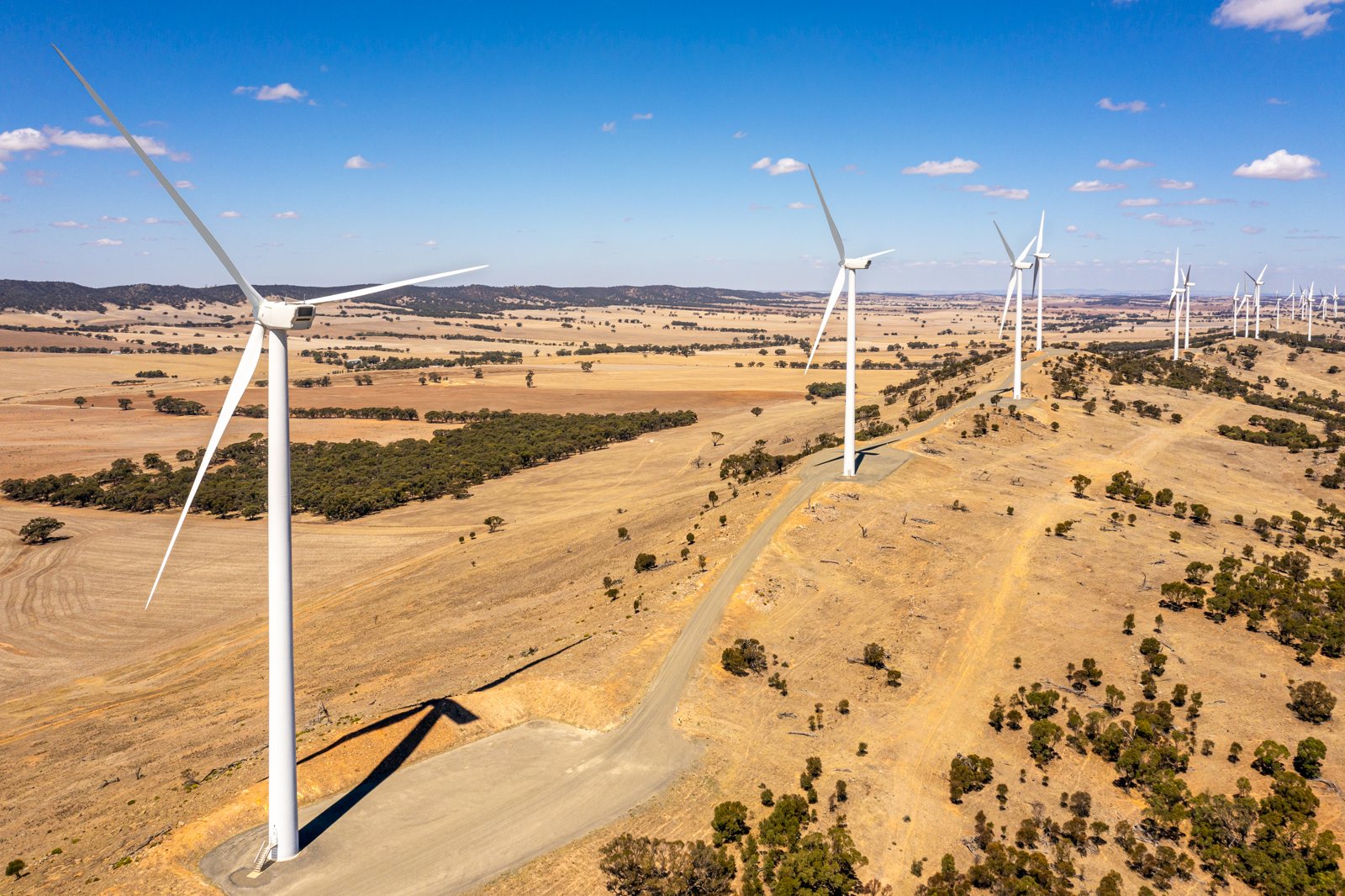 Aerial view of wind turbines along a ridge above dry farmland