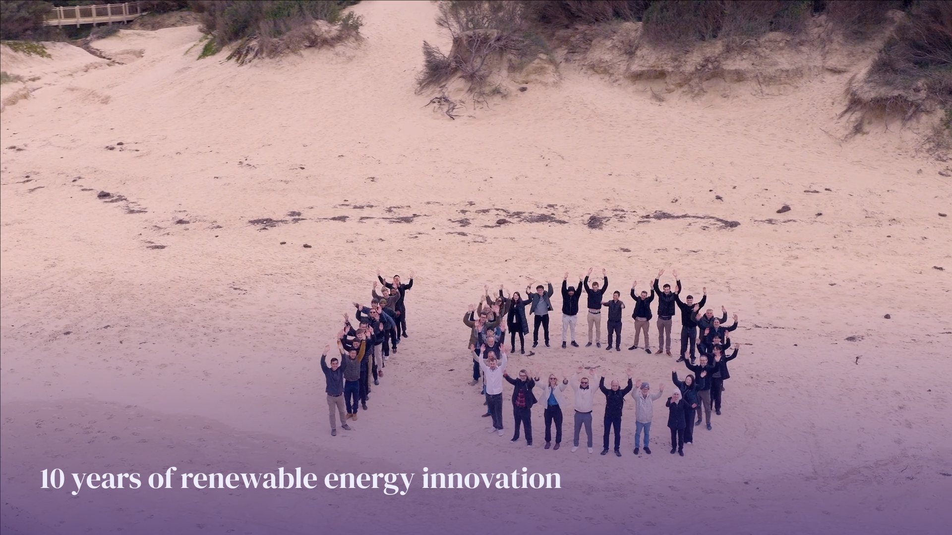 Proa team standing in a P shape on a beach, seen from above – 10 years of renewable energy innovation