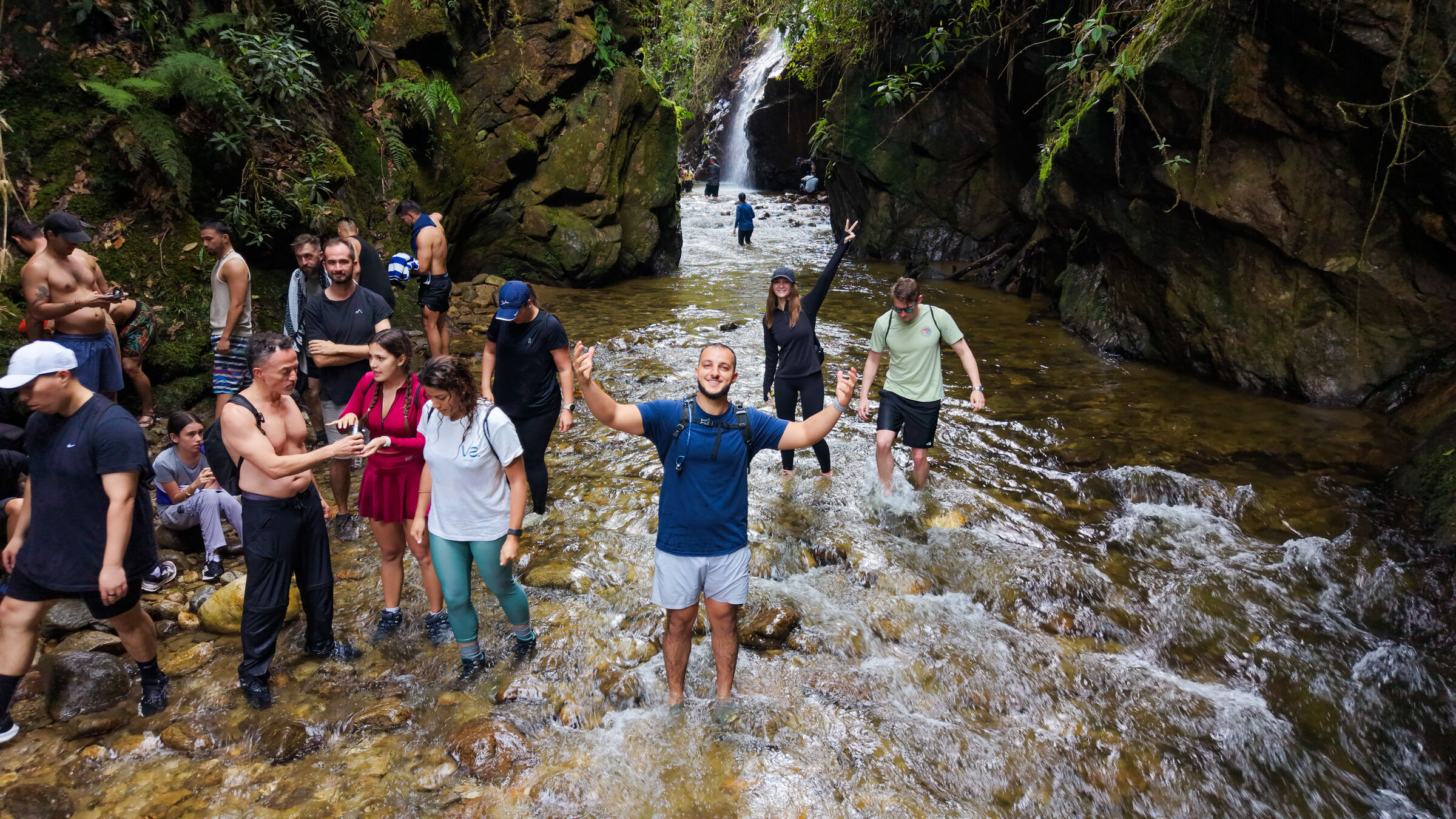 Founders Reset attendees wading up a jungle river toward a waterfall.