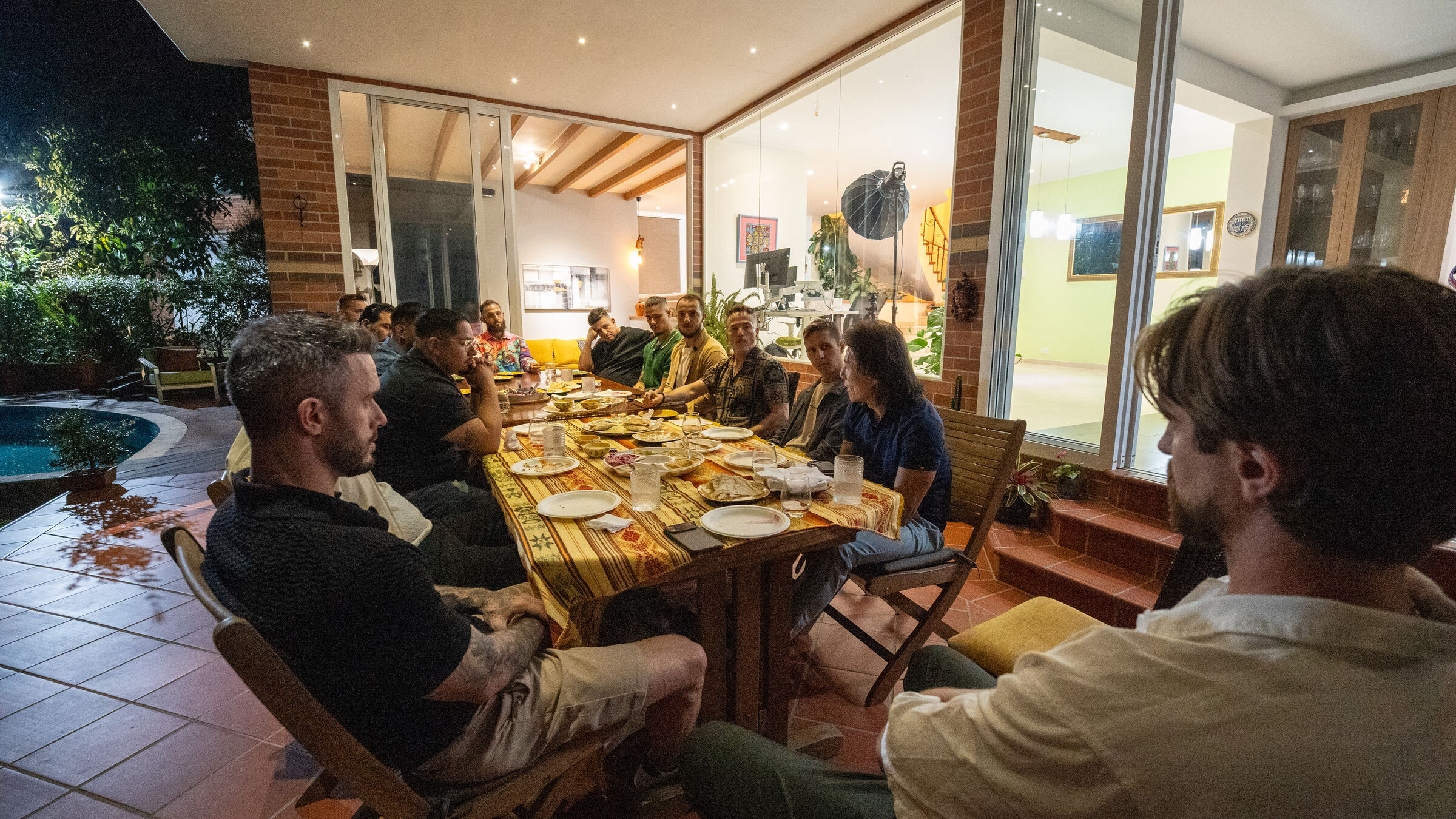 Guests around a long, candlelit dinner table on a terrace at a THE ONE founders dinner.