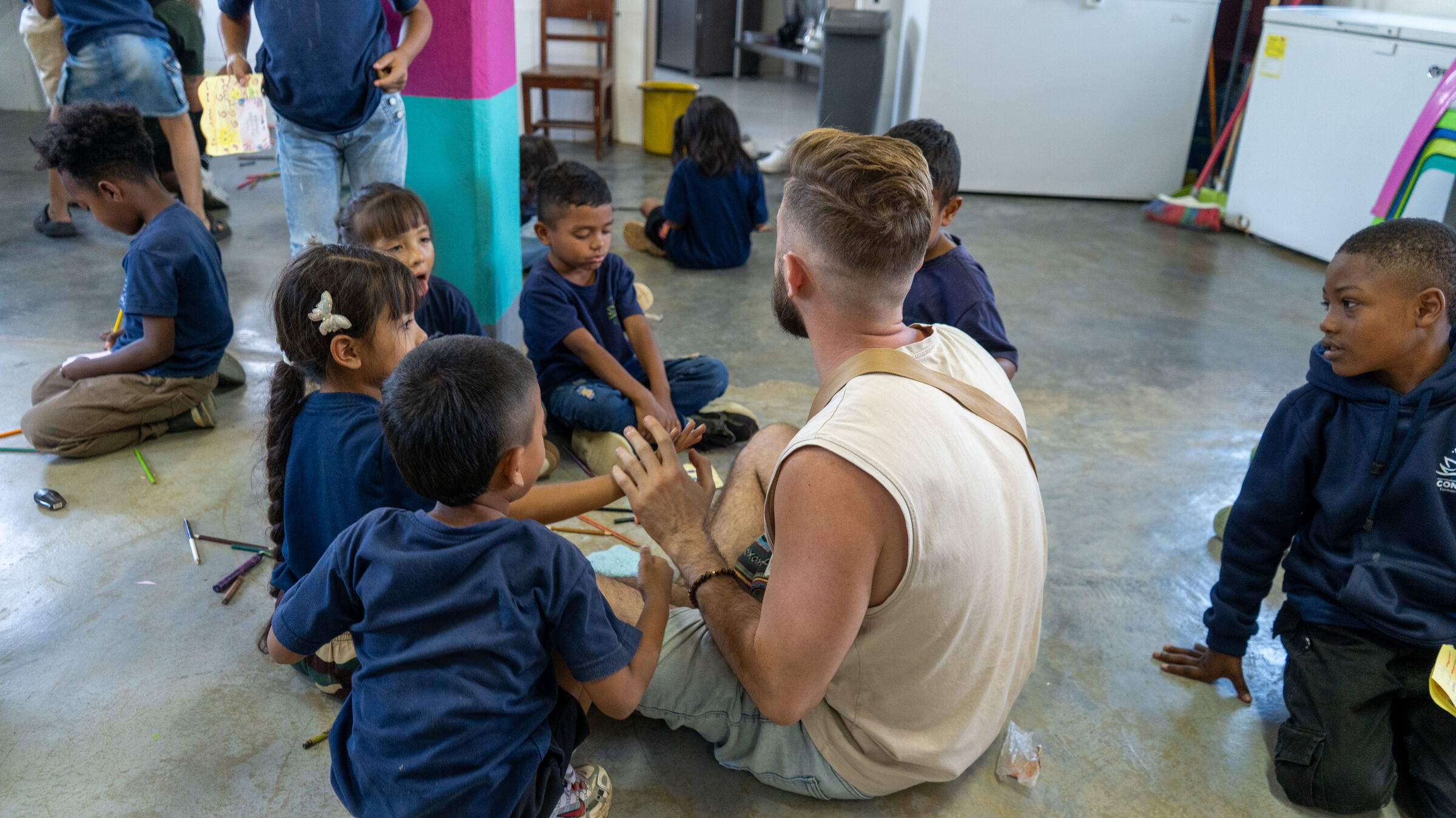 Volunteers sitting on the floor with children during a visit with Fundación Conciencia.