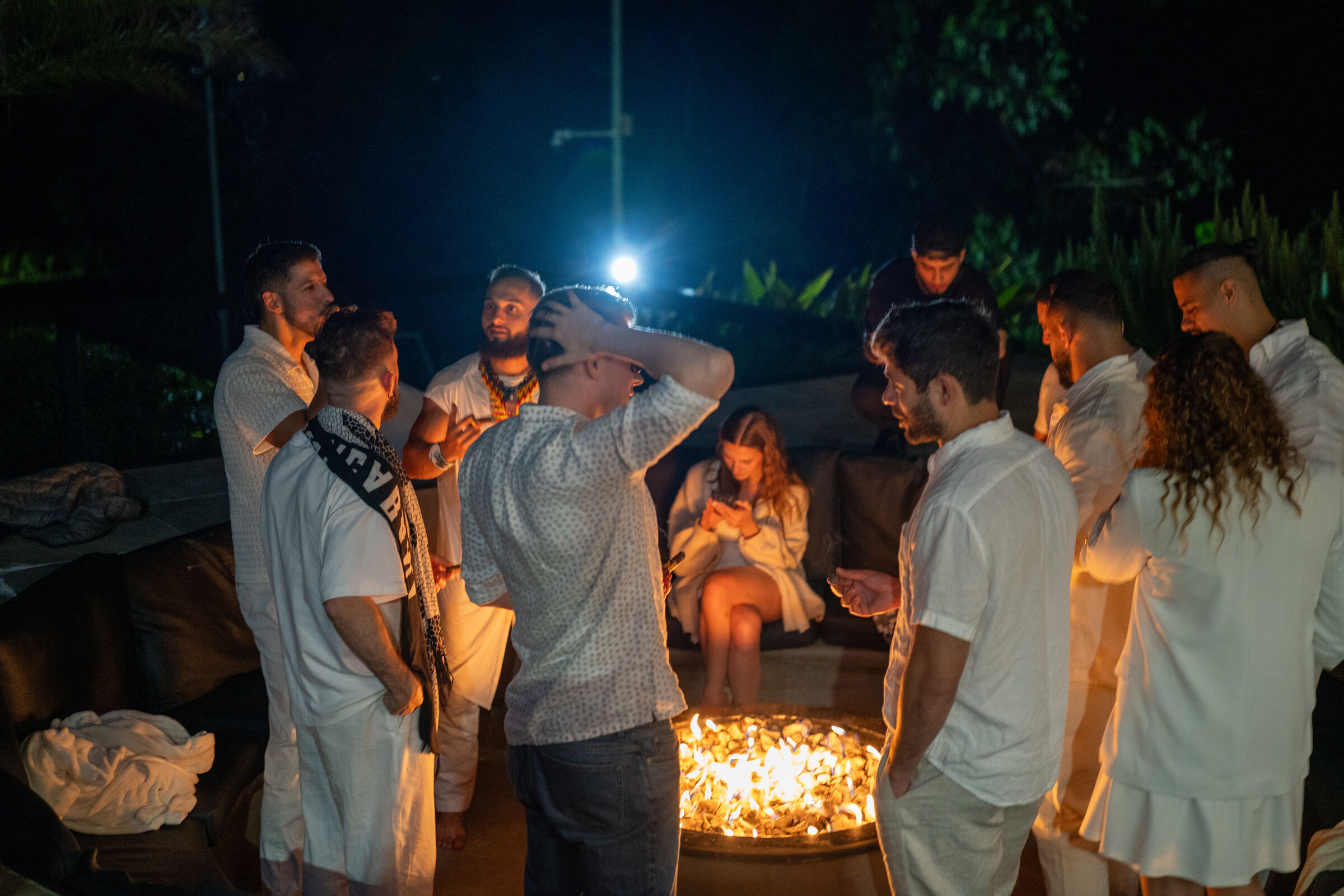Founders Reset attendees standing around a fire pit at night under string lights.