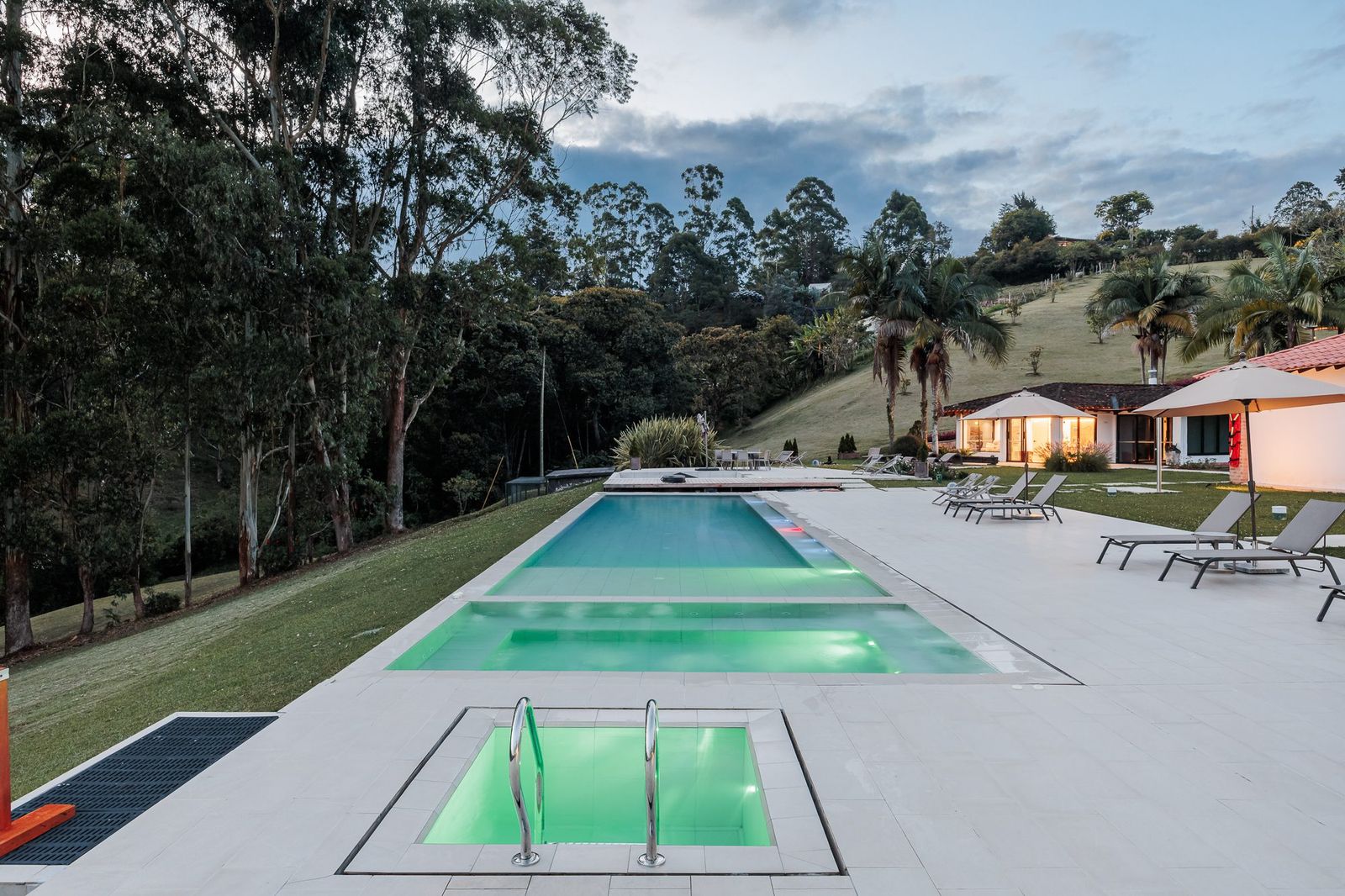 The pool and lit jacuzzi at Mountains of Hope at dusk.