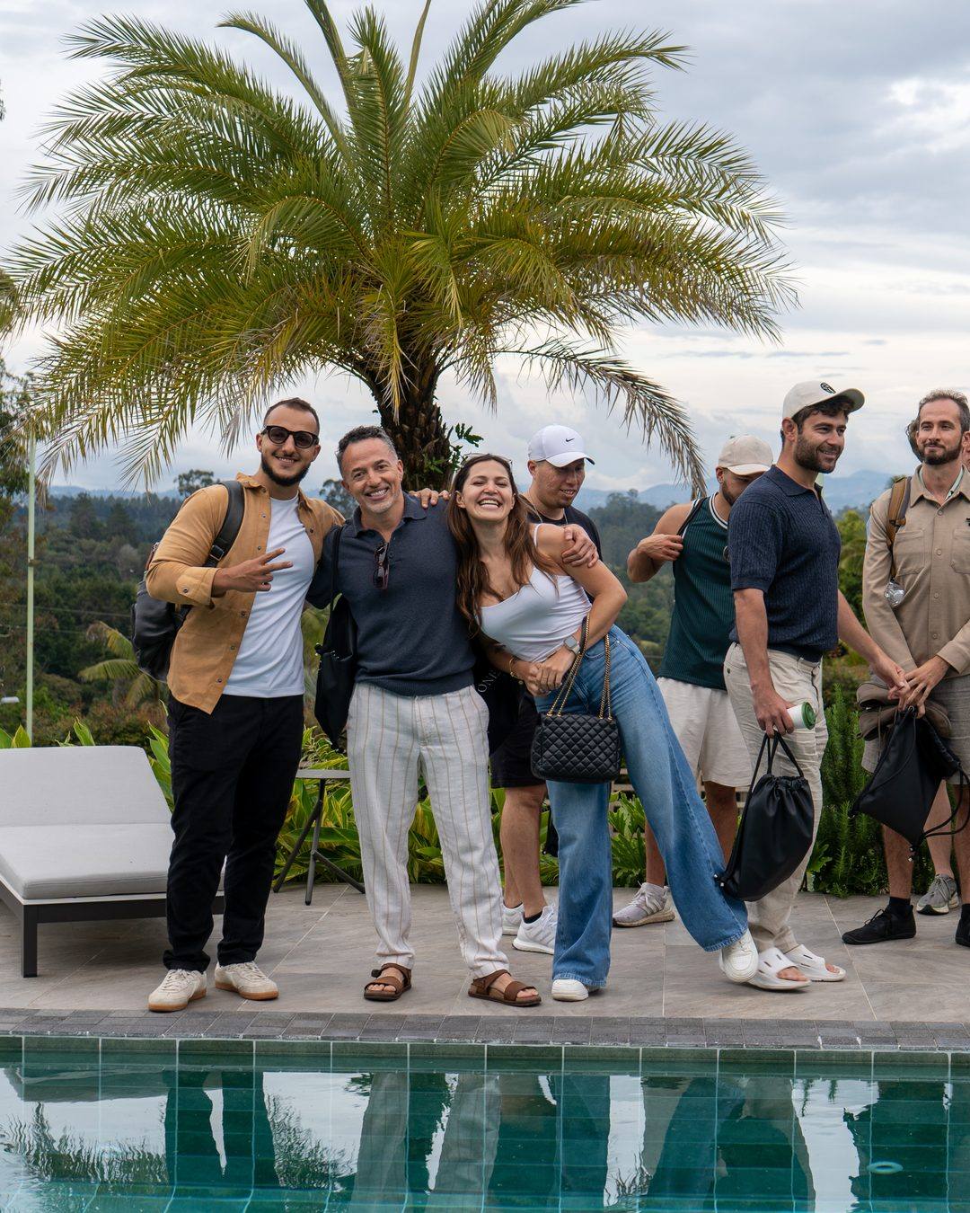 Founders Reset attendees smiling together by the pool, palms and mountains behind.