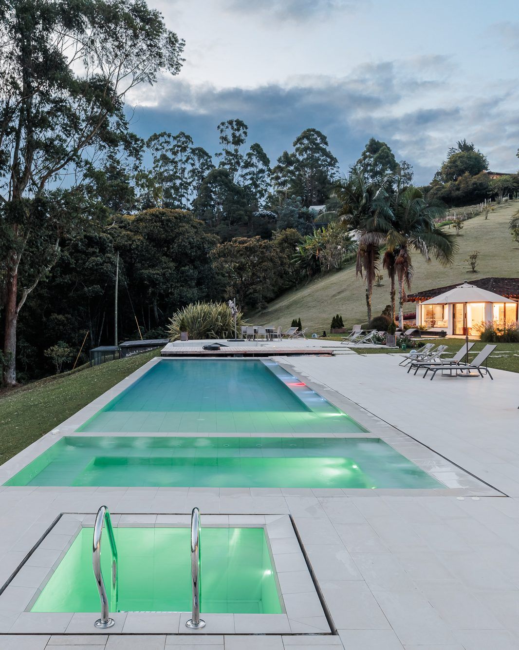 The pool and lit jacuzzi at Mountains of Hope at dusk.