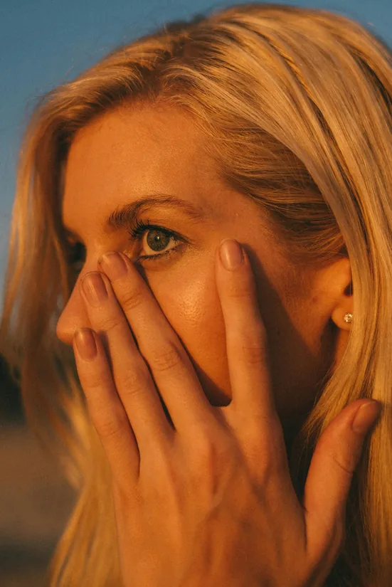 Patient with blonde hair touching her cheek