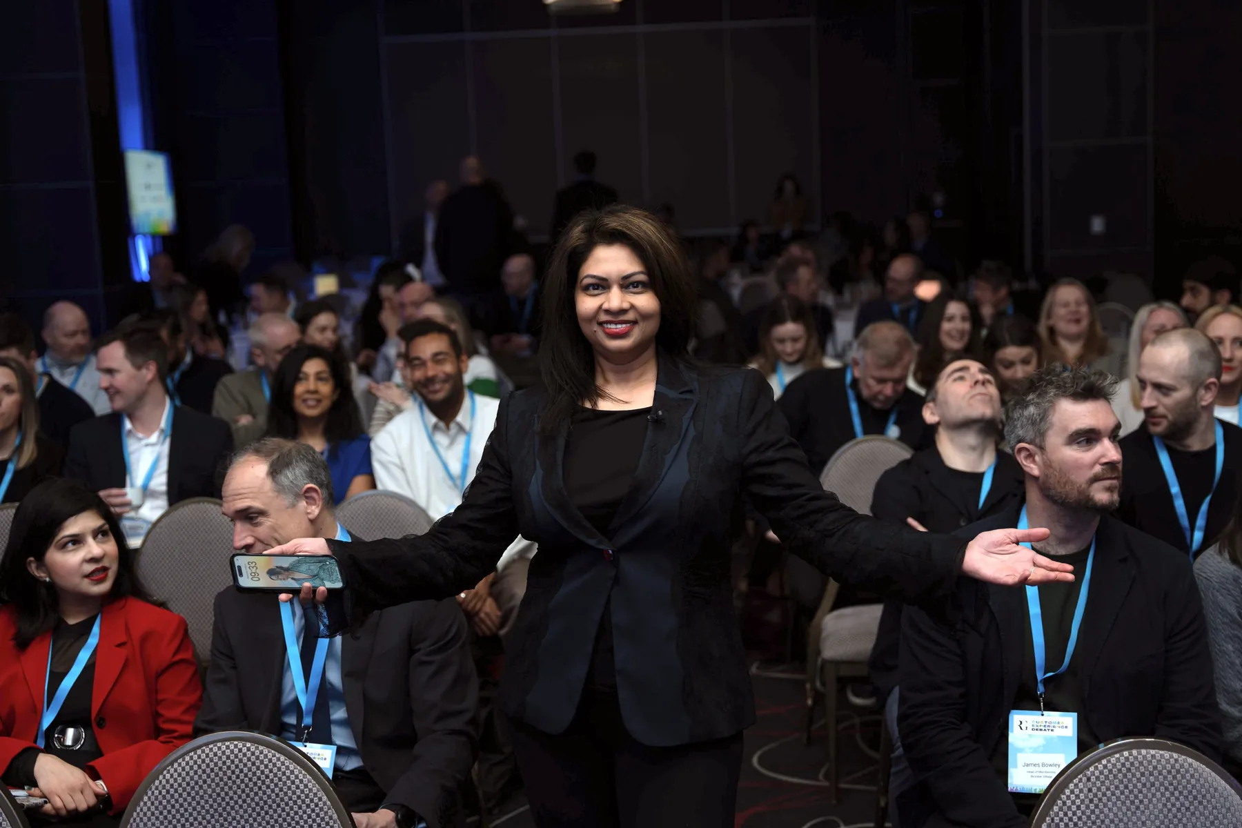Ruchira Neotia hosting a conference, arms open in front of a full audience