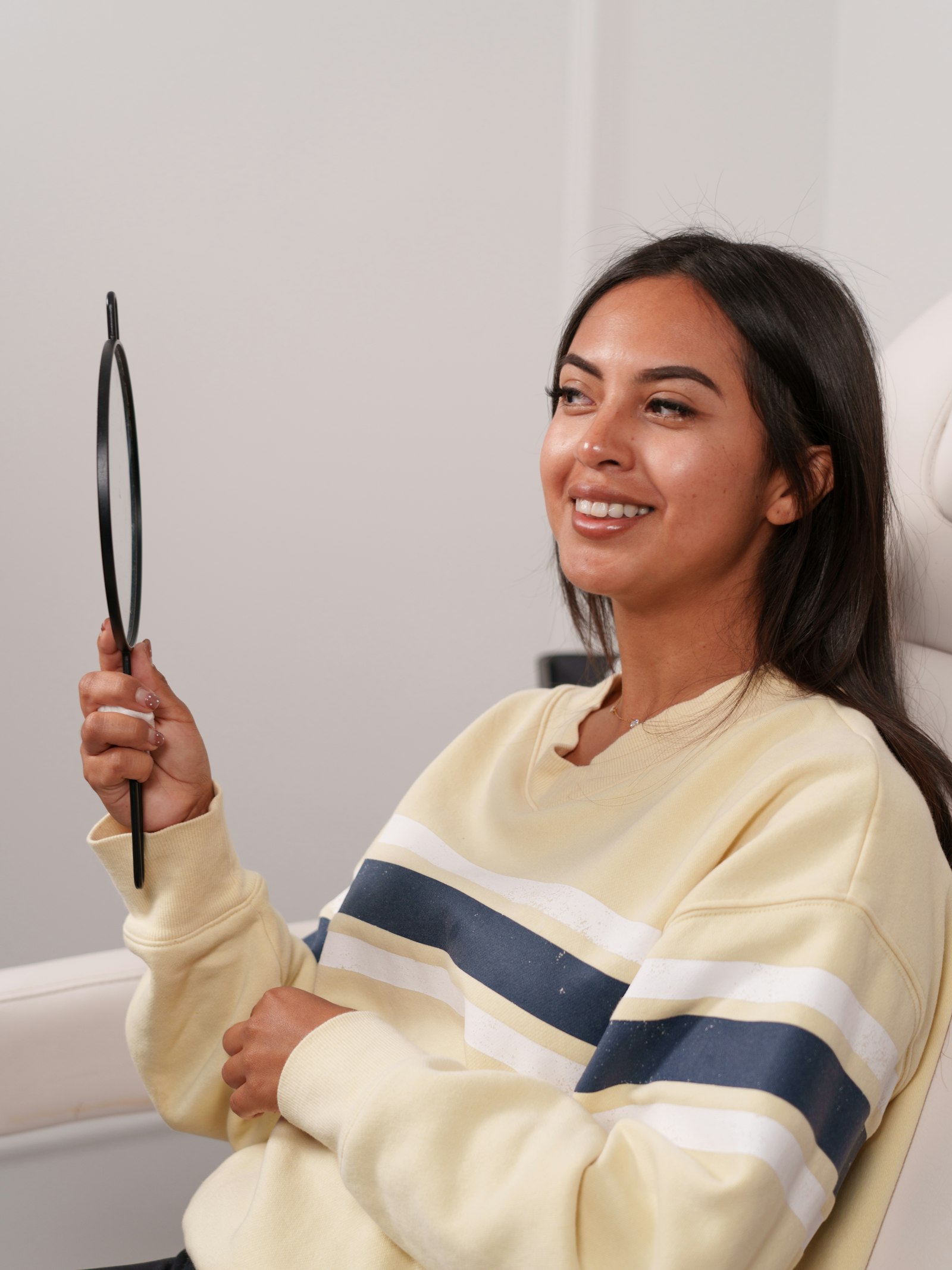 Smiling patient looking at her reflection in a hand mirror