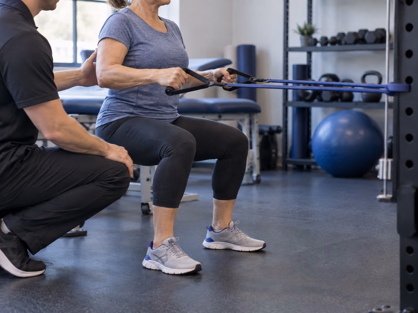 Woman performing a seated resistance-row exercise with a physiotherapist.