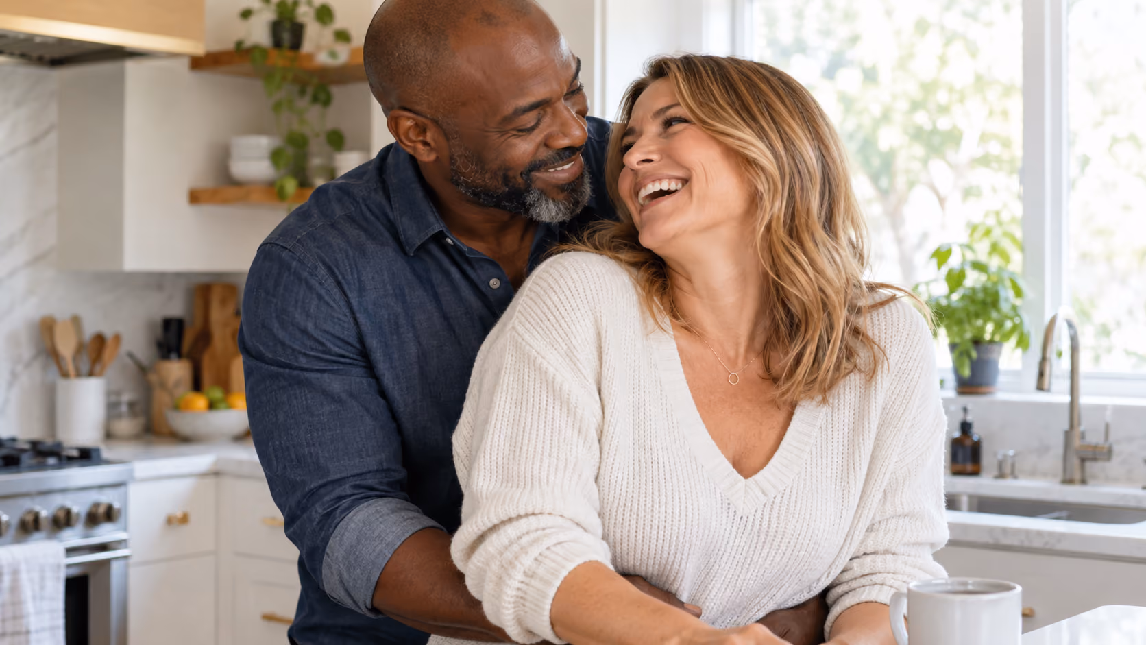 Middle-aged couple sharing a warm moment in a bright kitchen.